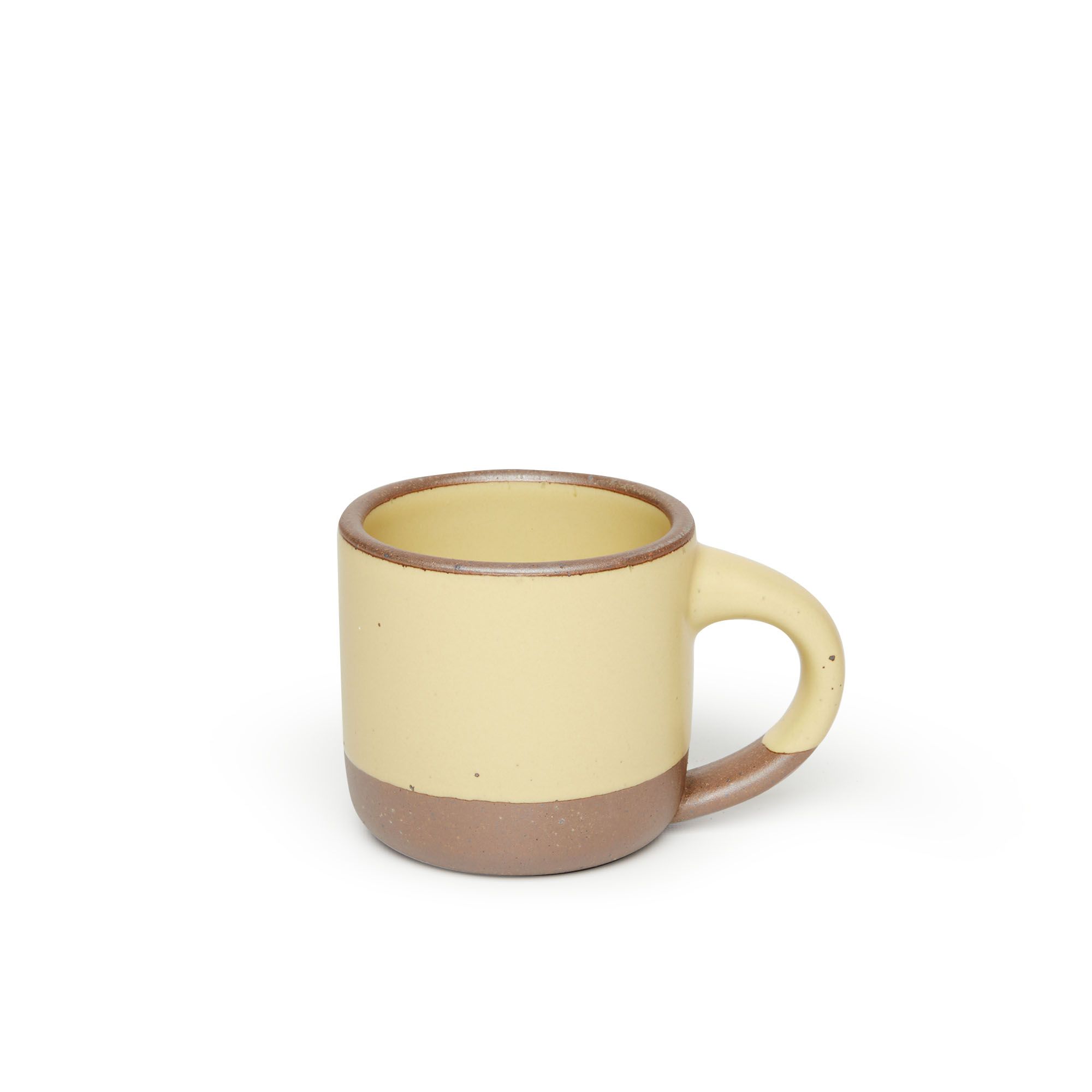 A small sized ceramic mug with handle in a light butter yellow glaze featuring iron speckles and unglazed rim and bottom base.