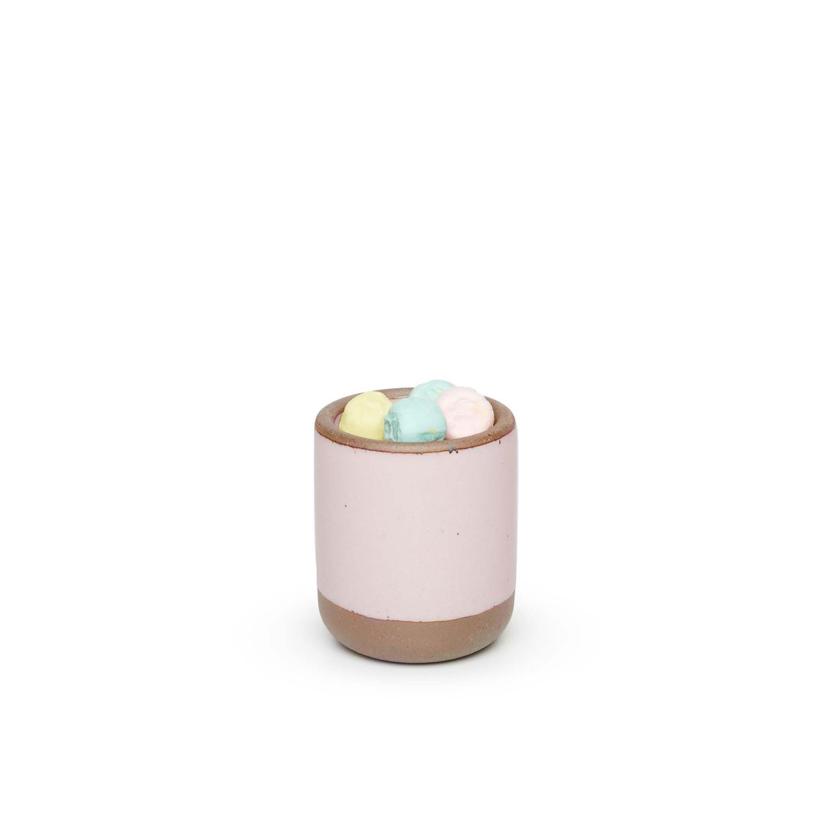 A small, short ceramic mug cup in a soft light pink color featuring iron speckles and unglazed rim and bottom base, filled with pastel marshmallows
