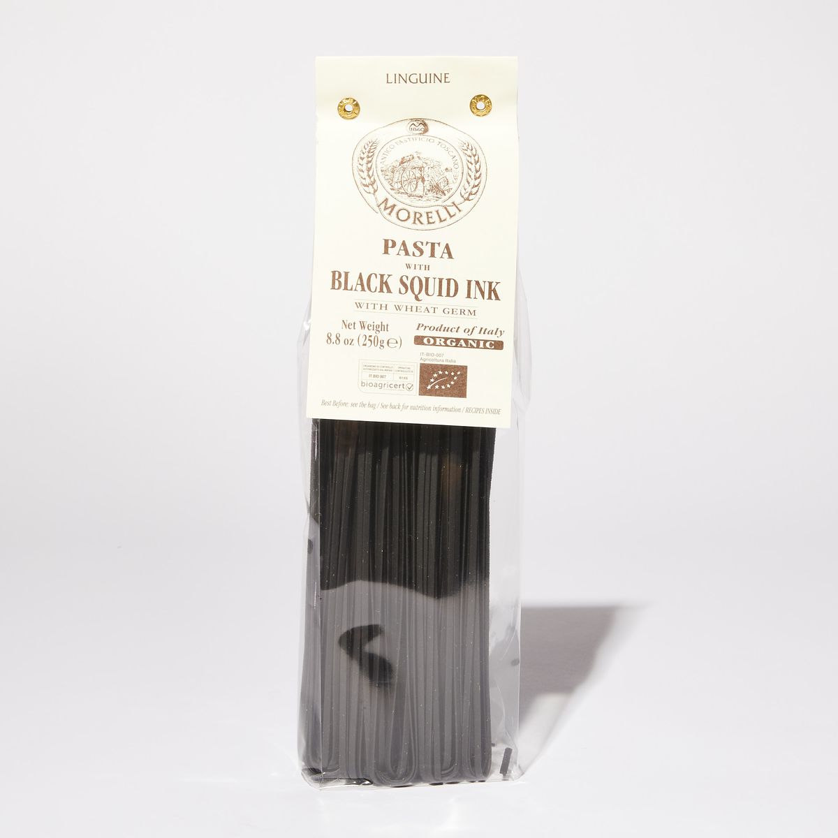 Black linguine inside a clear plastic bag with a white paper label that reads "Black Squid Ink Pasta"
