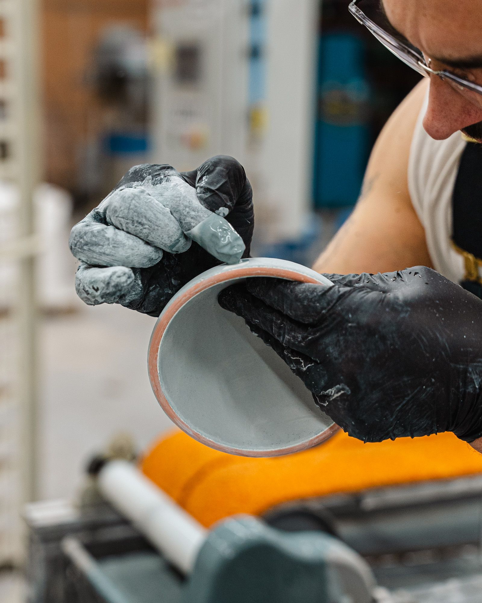 Hands holding a small ceramic bowl and carefully assessing the light blue glaze.