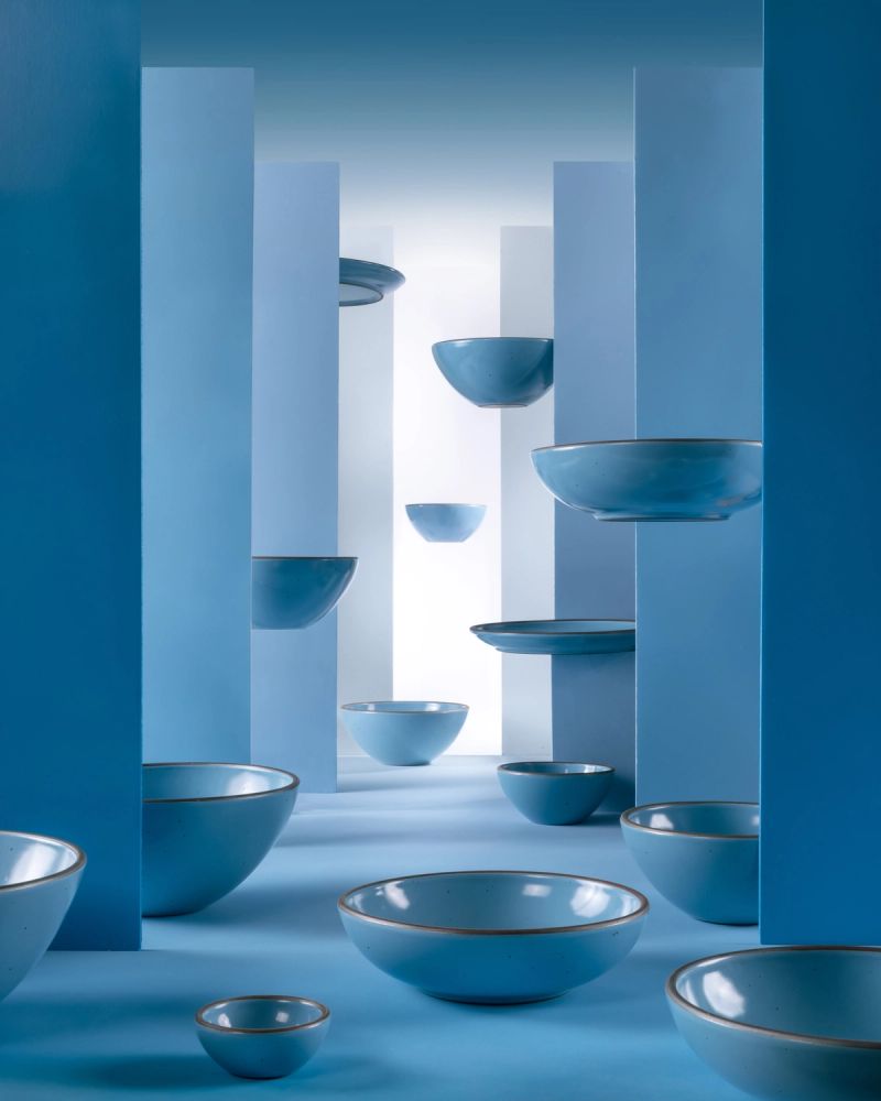 Ceramic bowls in a robin's egg blue color are artfully styled together among large walls in varying shades of blue. In the background, the bowls levitate in the air.