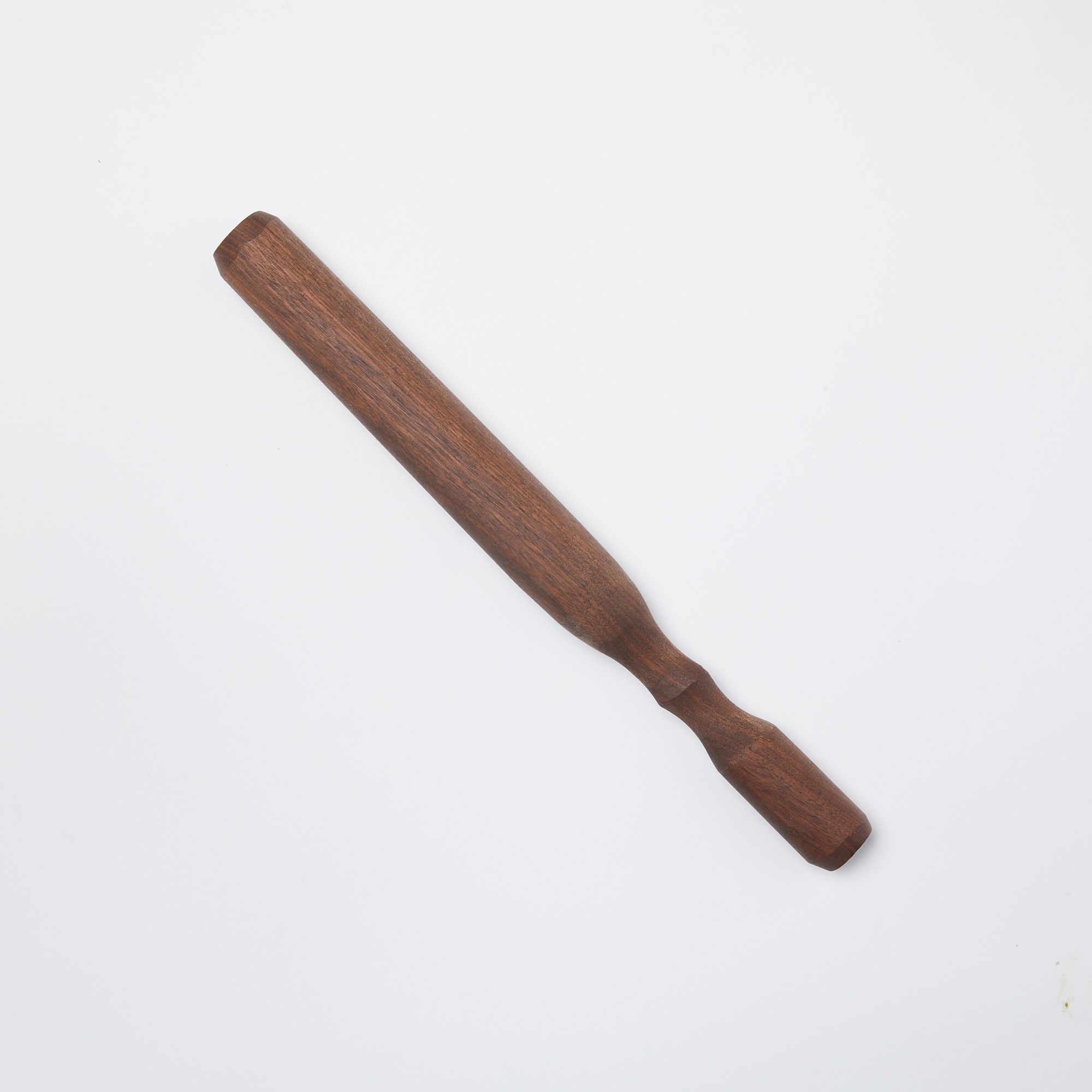 Long walnut wood cocktail muddler that tapers slightly towards the handle