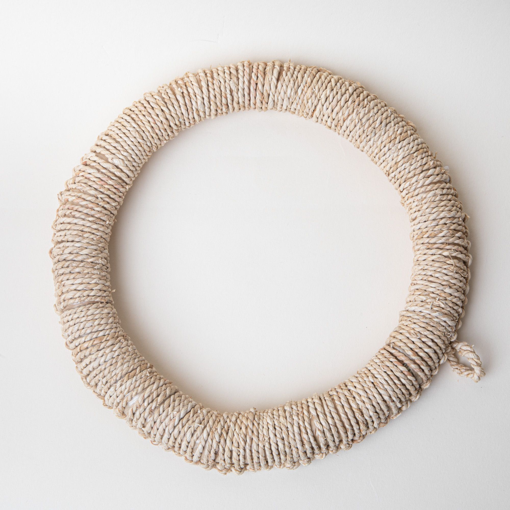 Circle ring trivet wrapped in woven organic material in a neutral color.