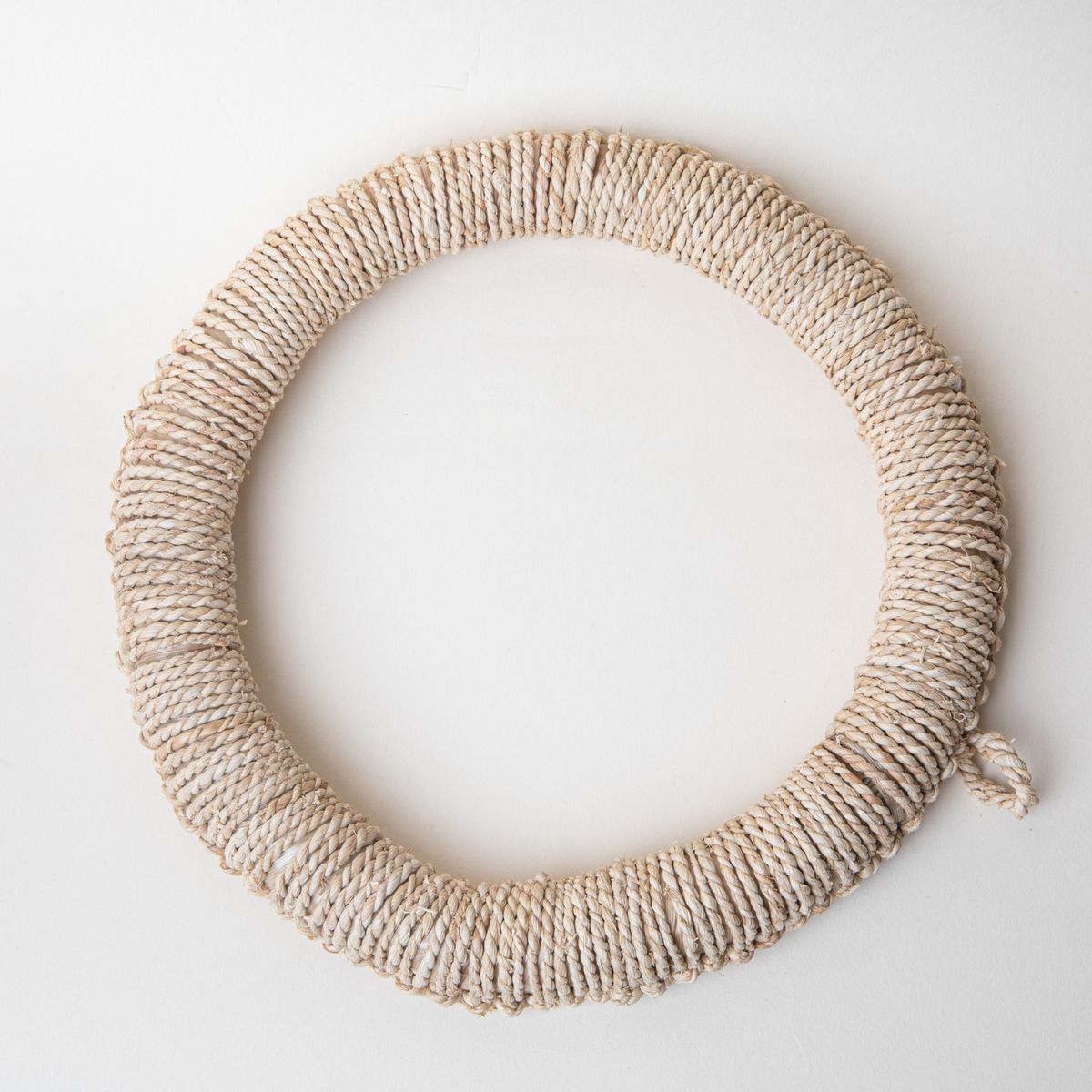 Circle ring trivet wrapped in woven organic material in a neutral color