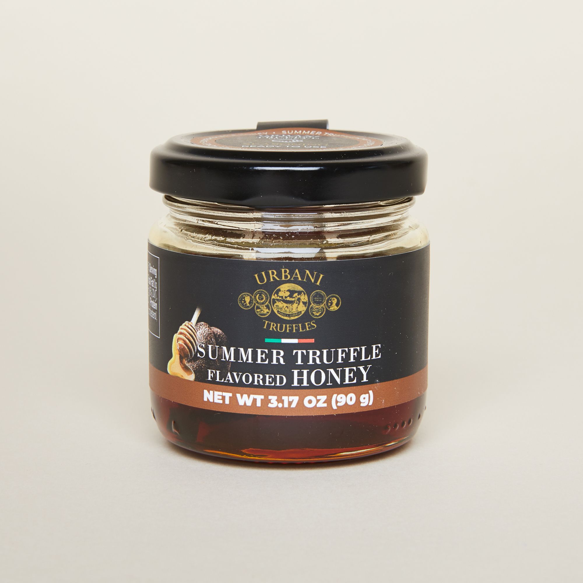 A stout glass container with a black lid and black label that reads Urbani Black Truffle Chestnut Honey