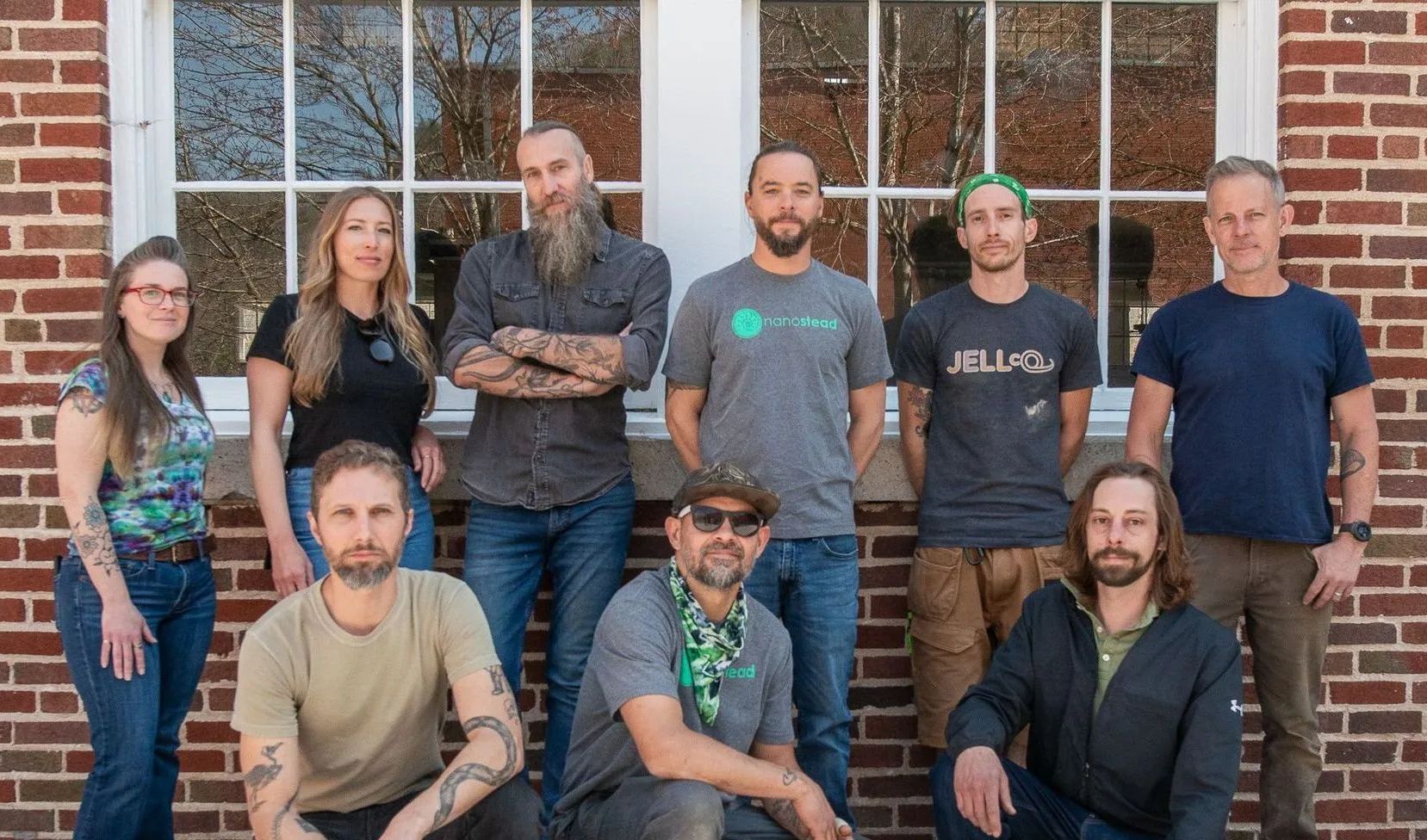 A group of people are gathered outside in front of a building staring at the camera.