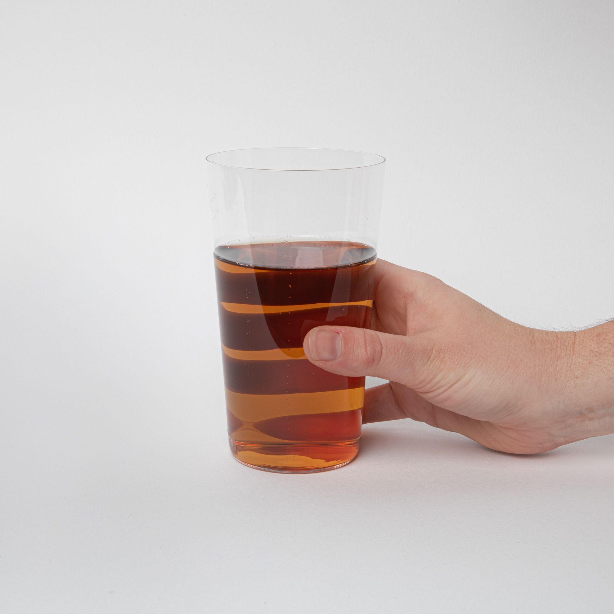 A hand holding a clear simple beer glass filled with beer