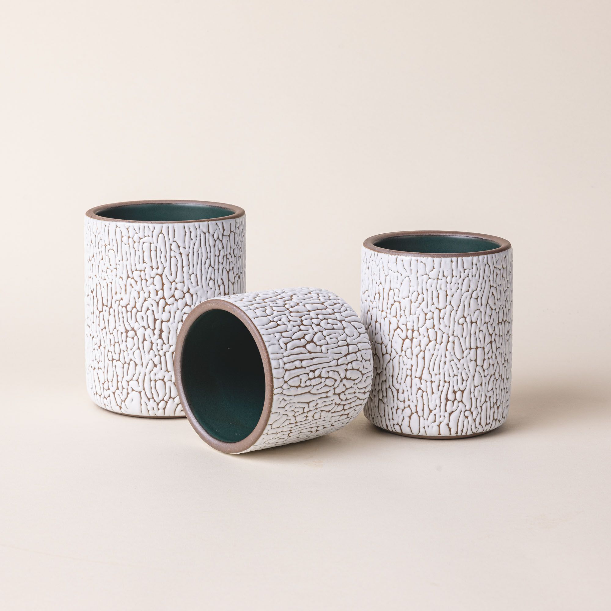 Three white ceramic vessels in Small, Medium, and Big with cracked texture and the interior being dark teal