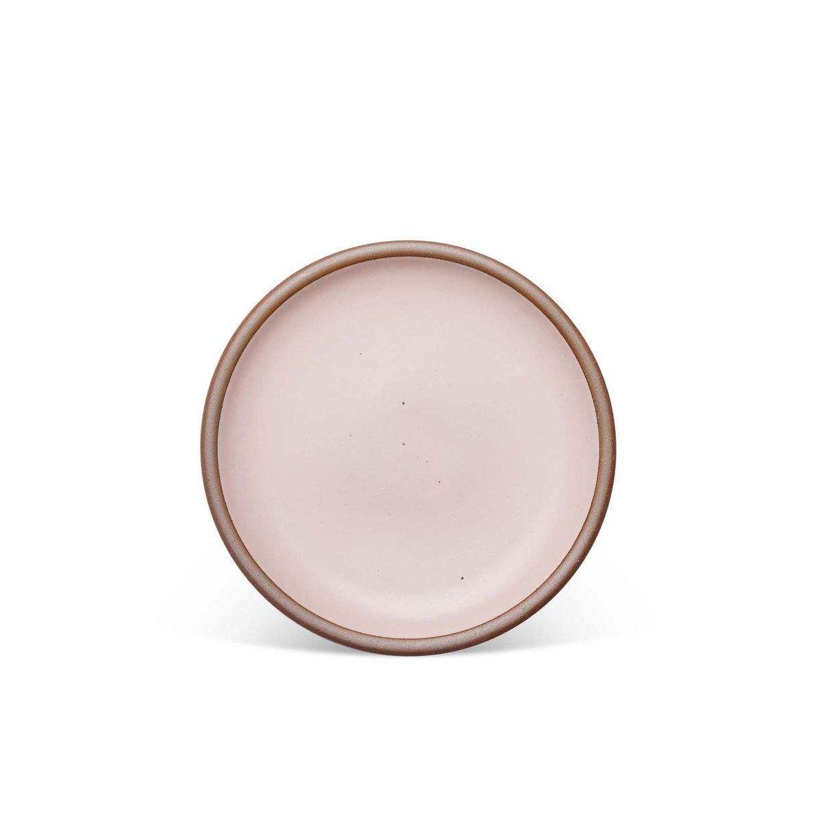 A medium sized ceramic plate in a soft light pink color featuring iron speckles and an unglazed rim
