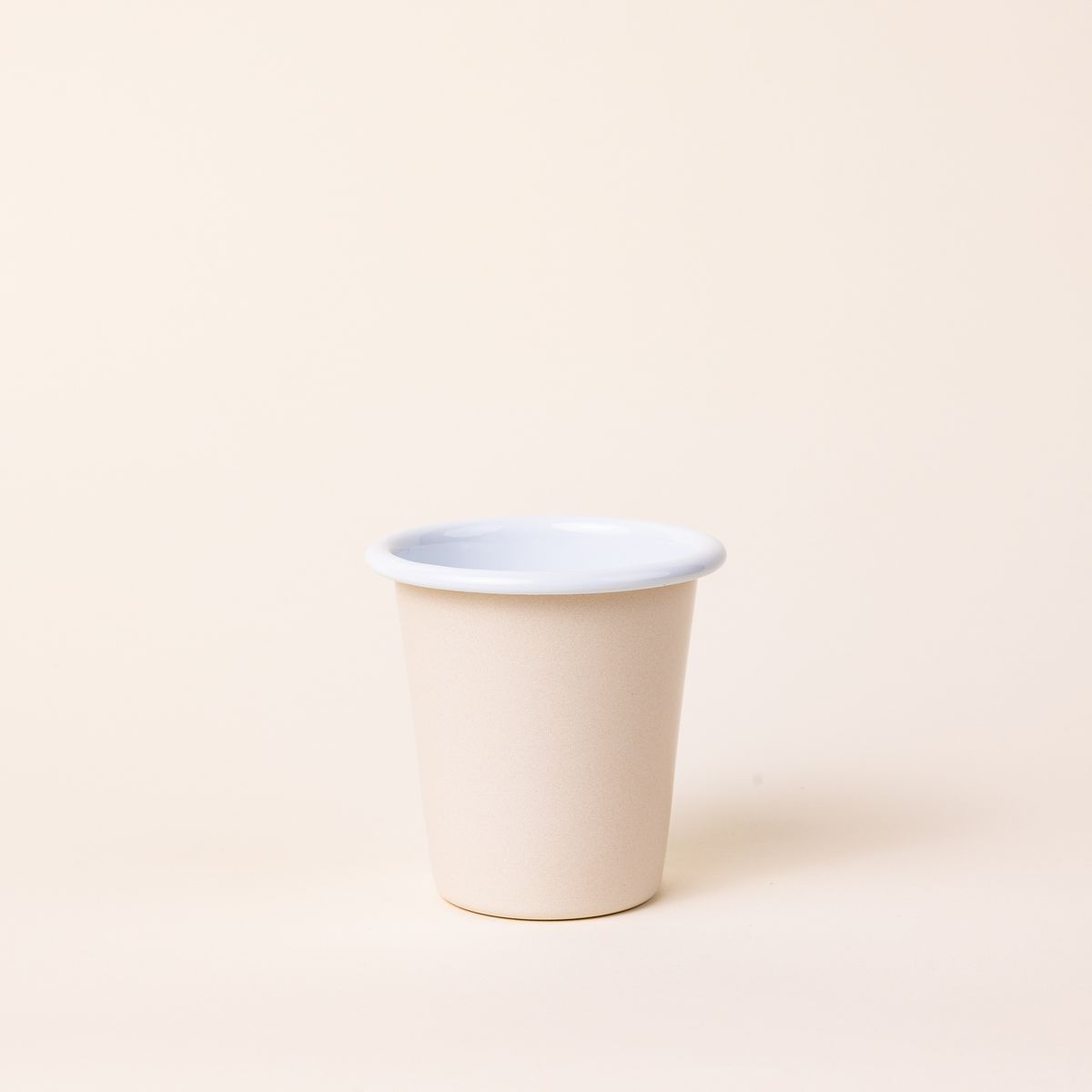 A short enamel cup with a cream exterior and white interior