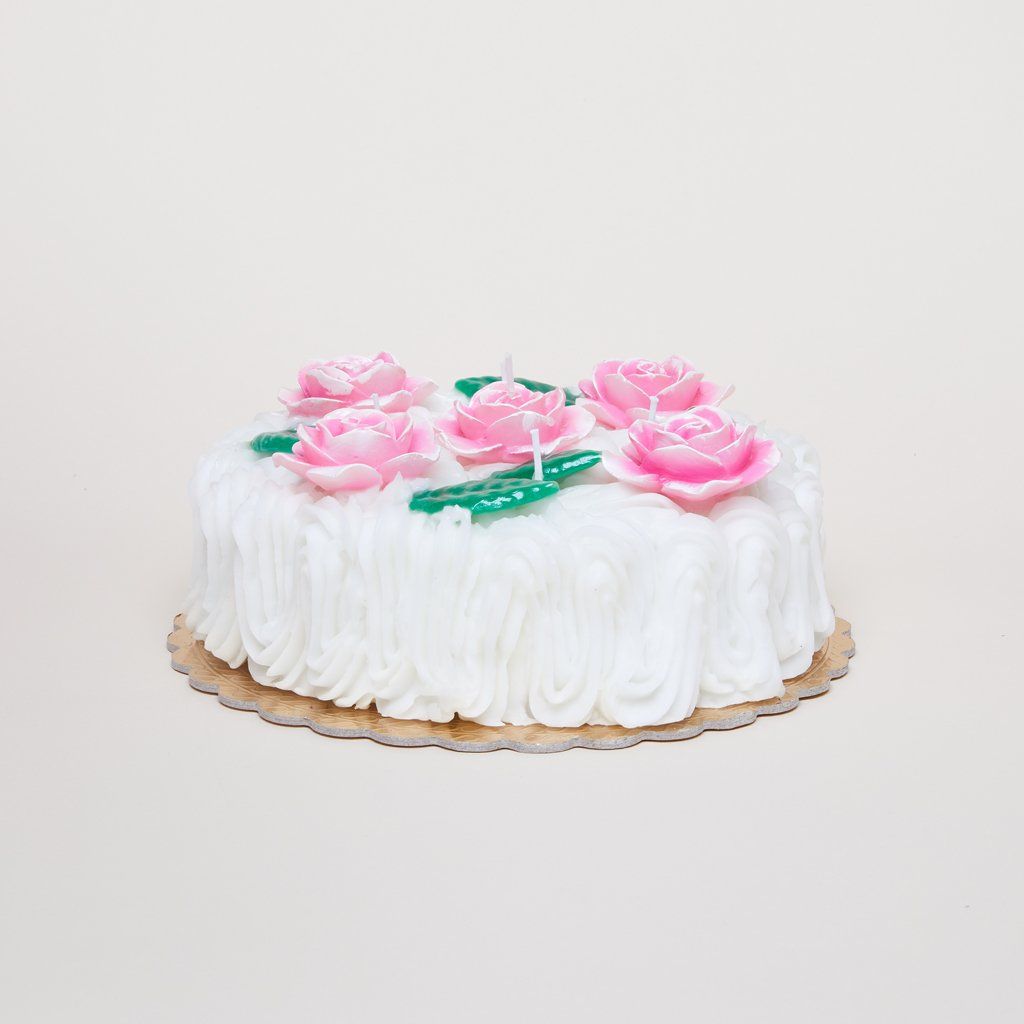 A pink, white and green candle made to resemble a cake with icing