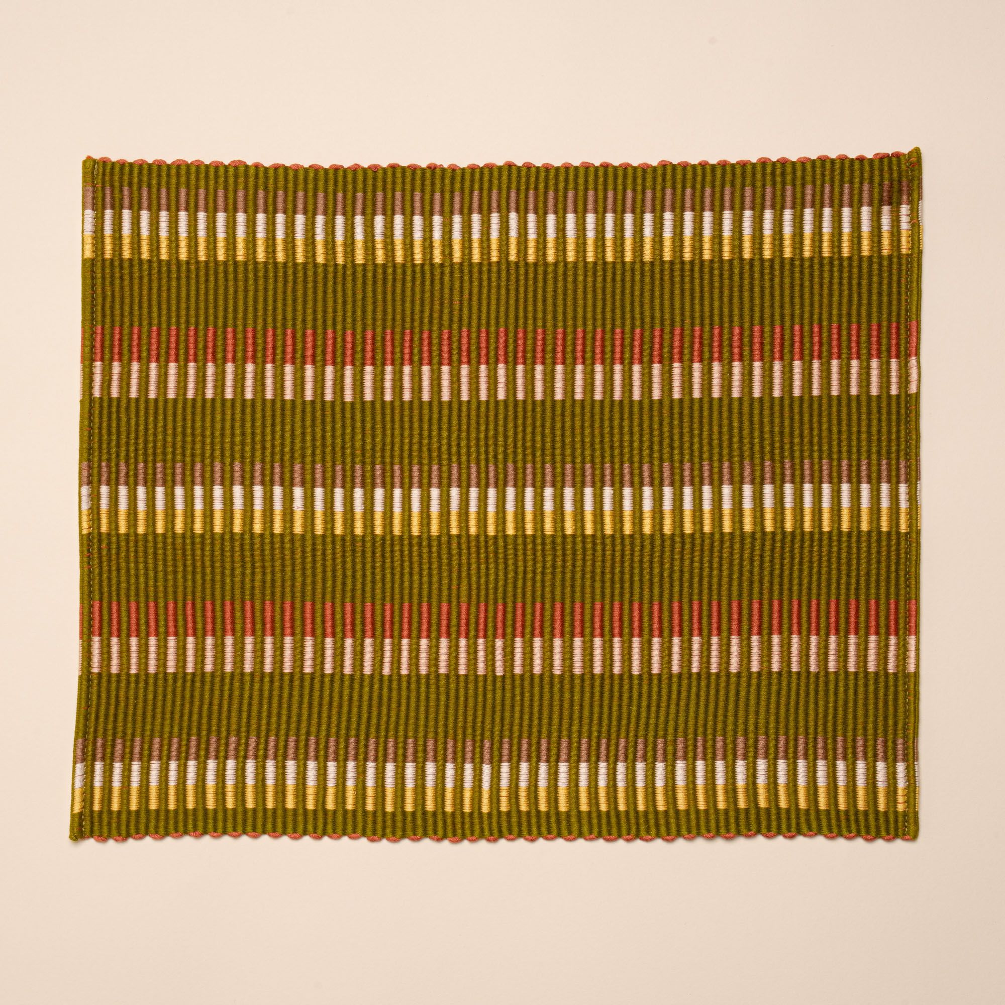 Rectangle placemat with offset stripe design that is hand woven in olive, tan, orange, and yellow colors