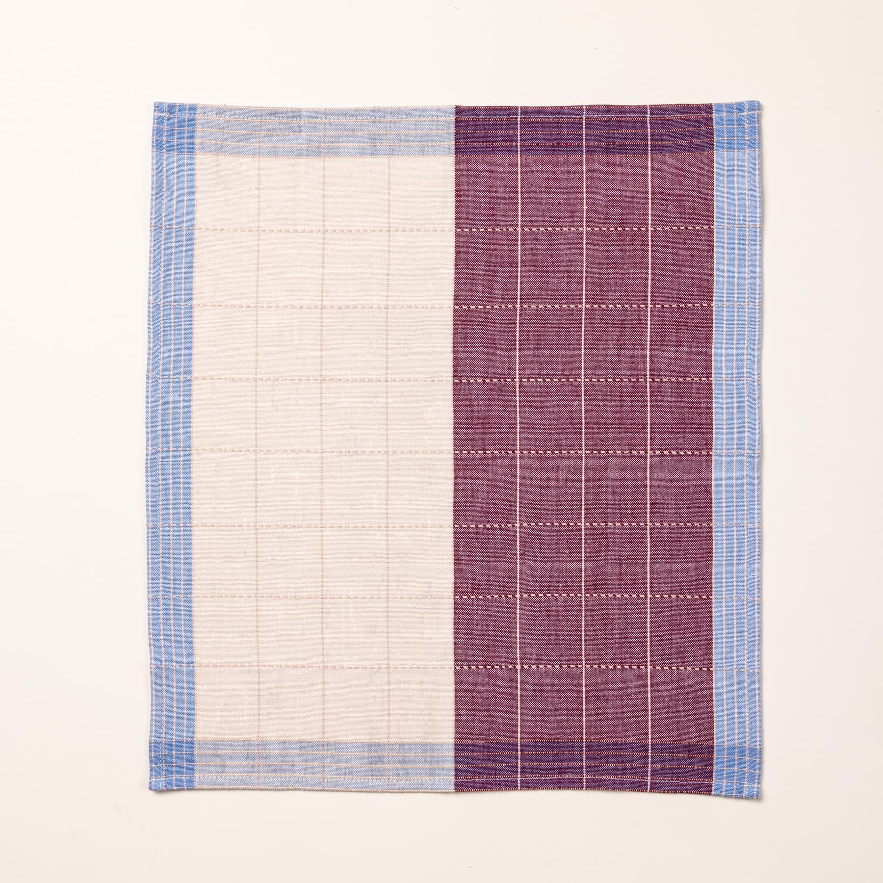 A flat plaid napkin in plum and periwinkle colors with white gridlines.