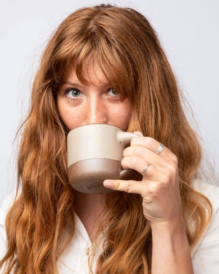 Woman holding the small mug up to take a sip