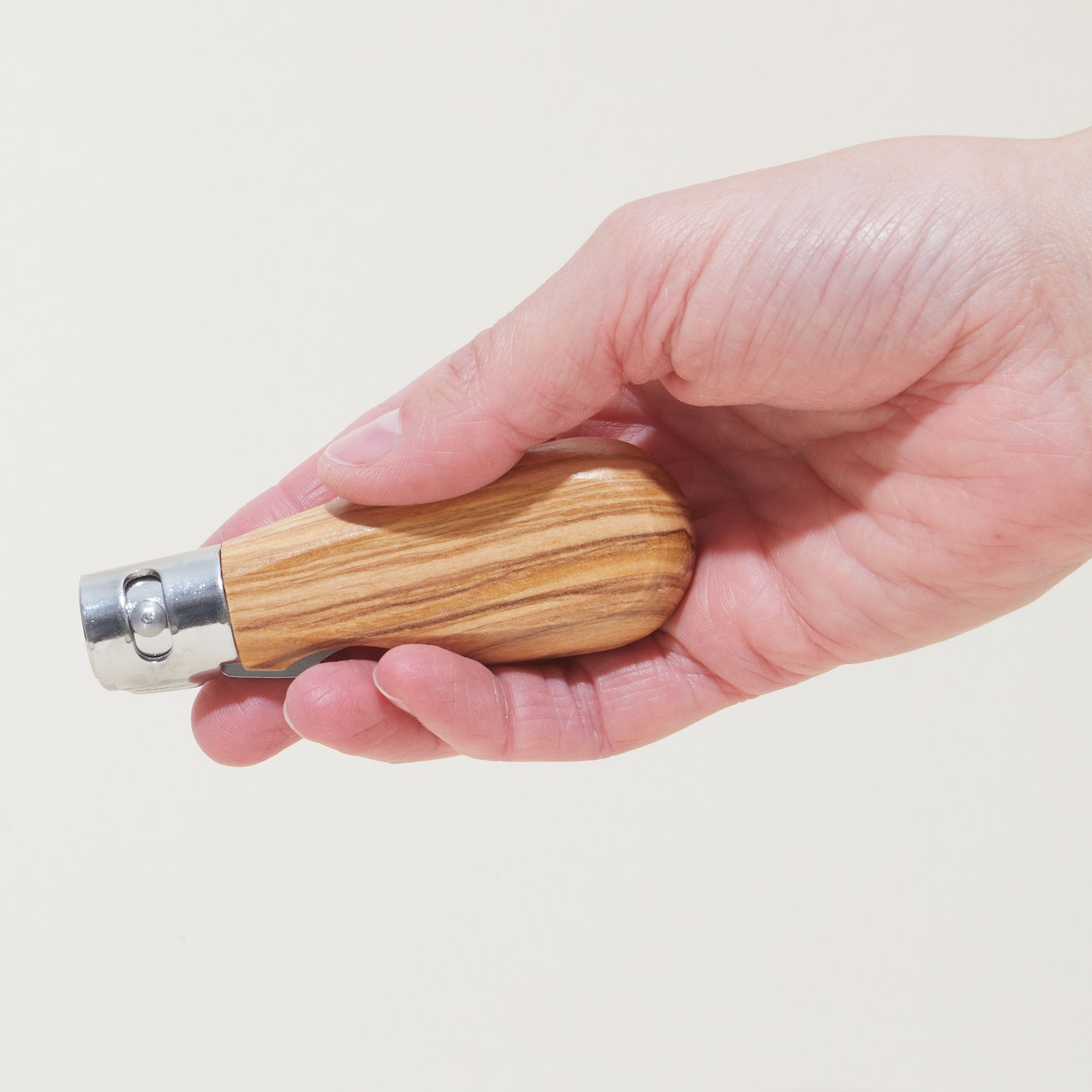 Hand holding a closed pocket knife with an olivewood handle