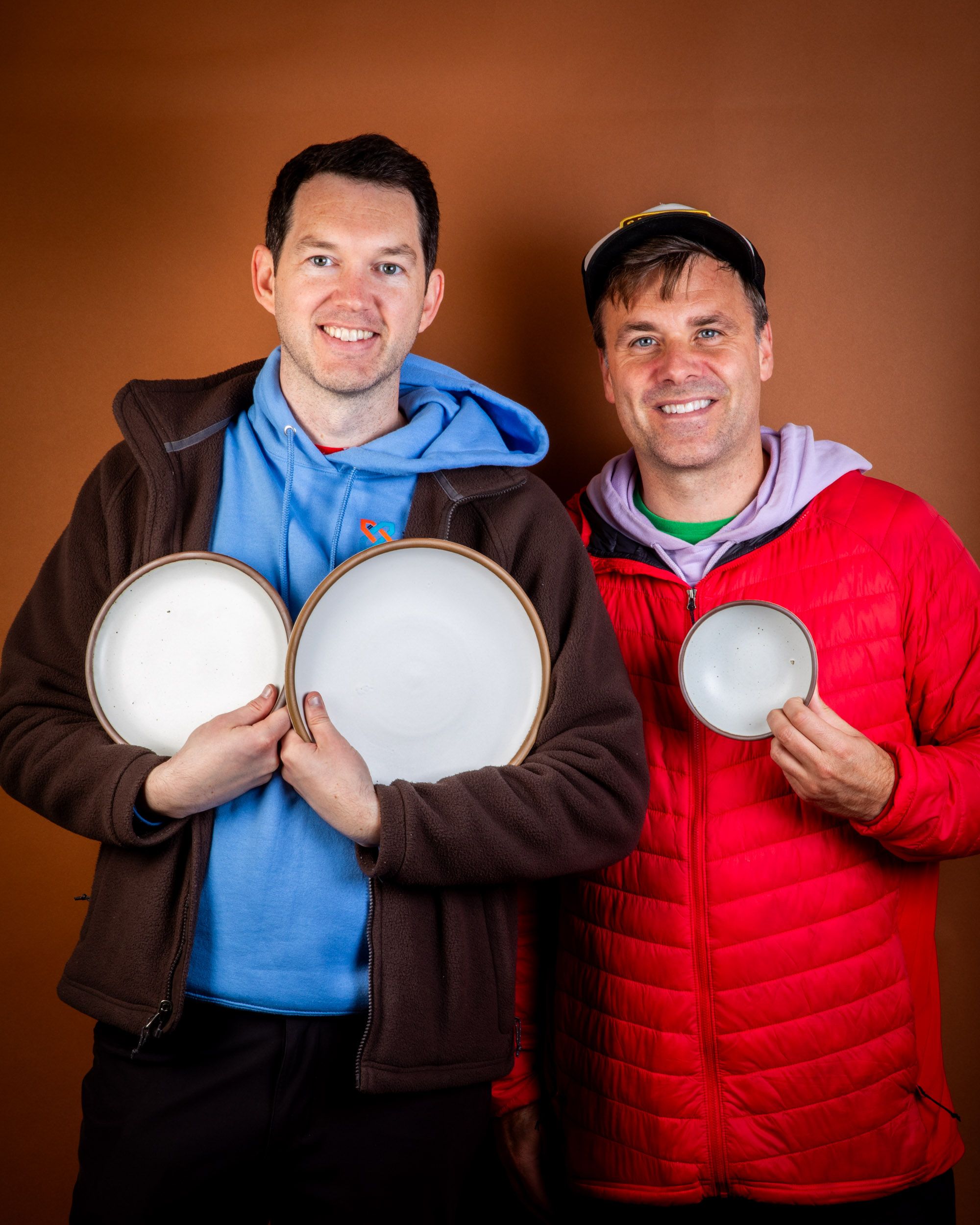Chuck and Glen of @eastforkpotheads holding ceramic plates and bowls in a cool white color.