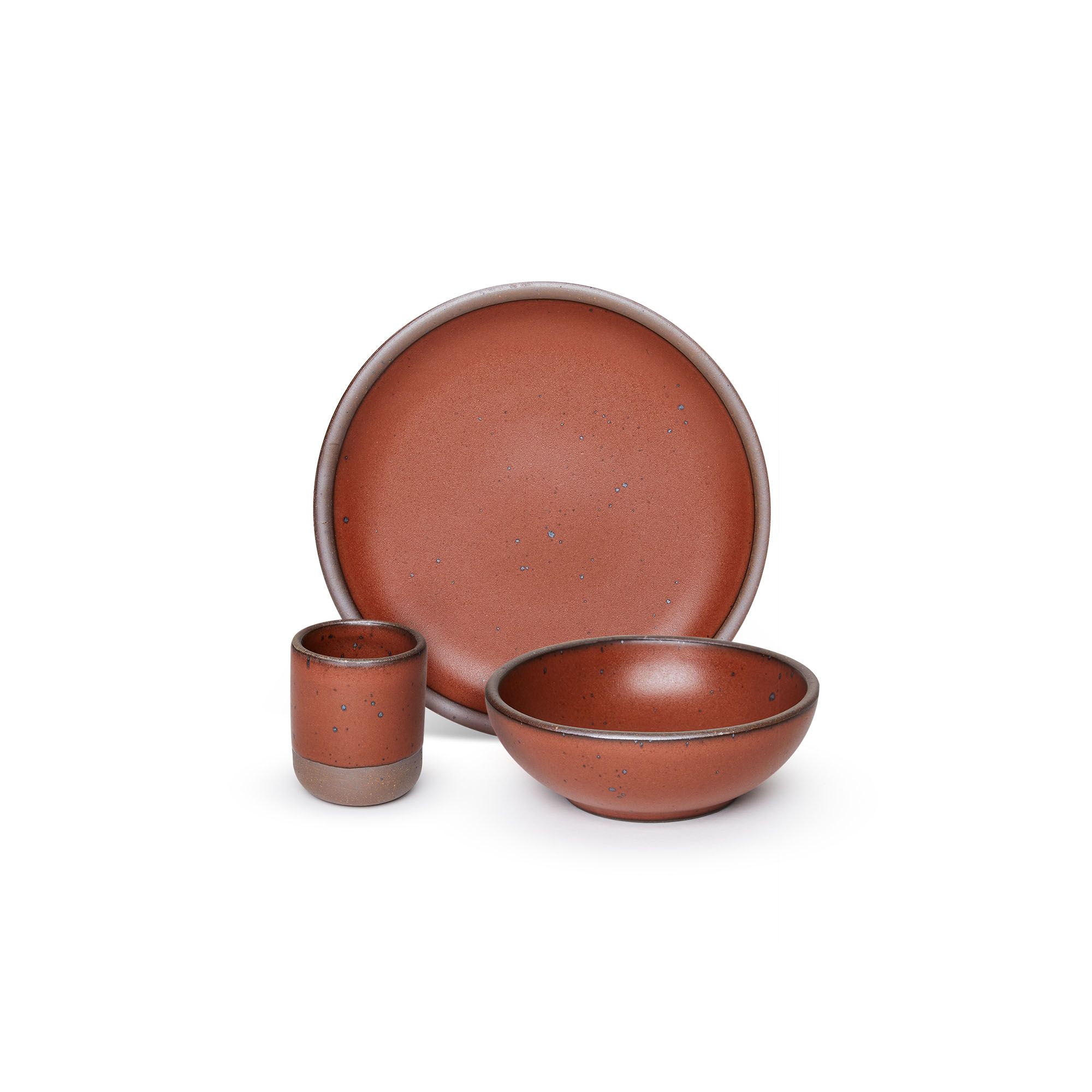 A small tiny cup, a medium sized plate, and a small breakfast bowl paired together in a cool burnt terracotta color featuring iron speckles.