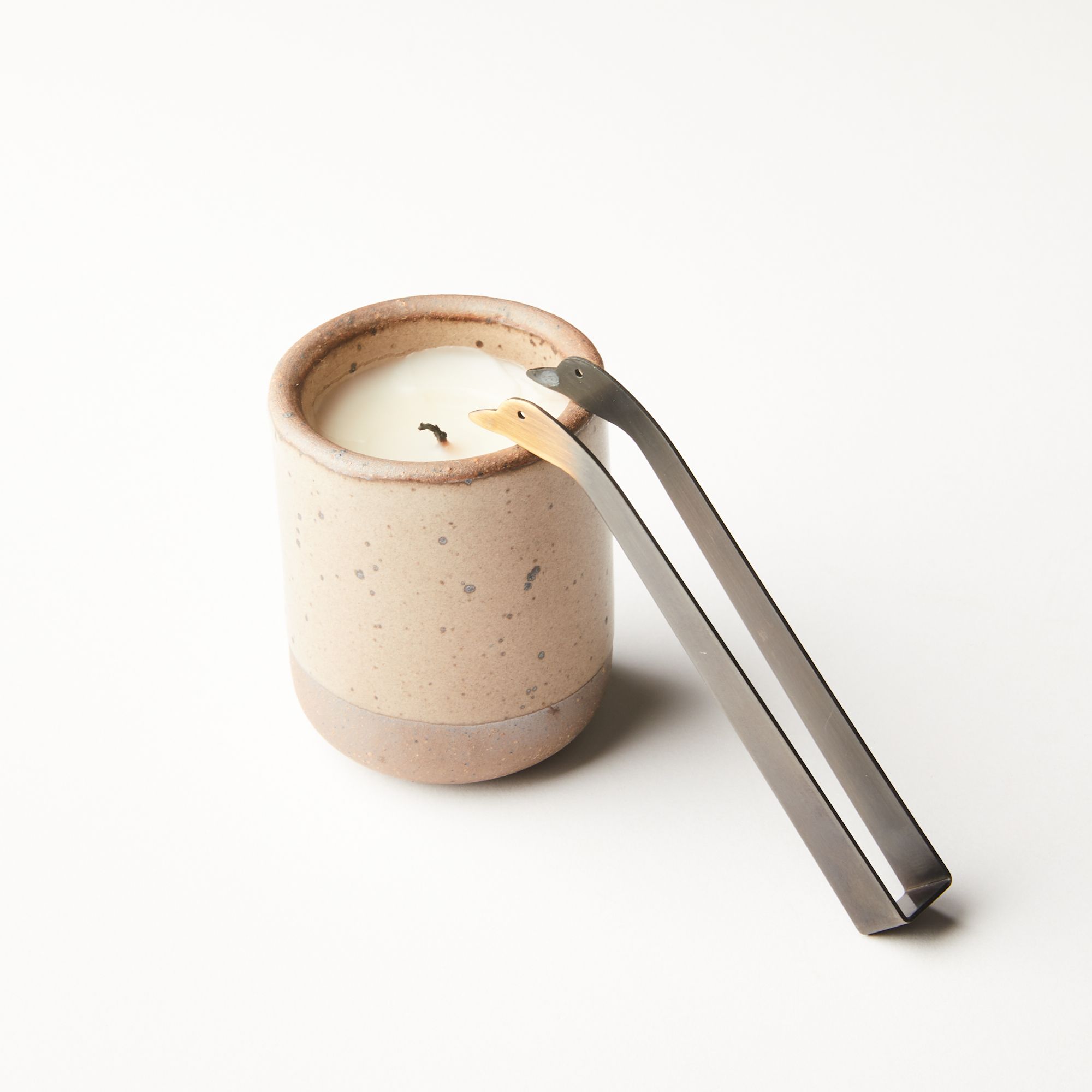 Simple steel clamp candle snuffer with a tip that is a duck head silhouette with eyes - leaning on a candle