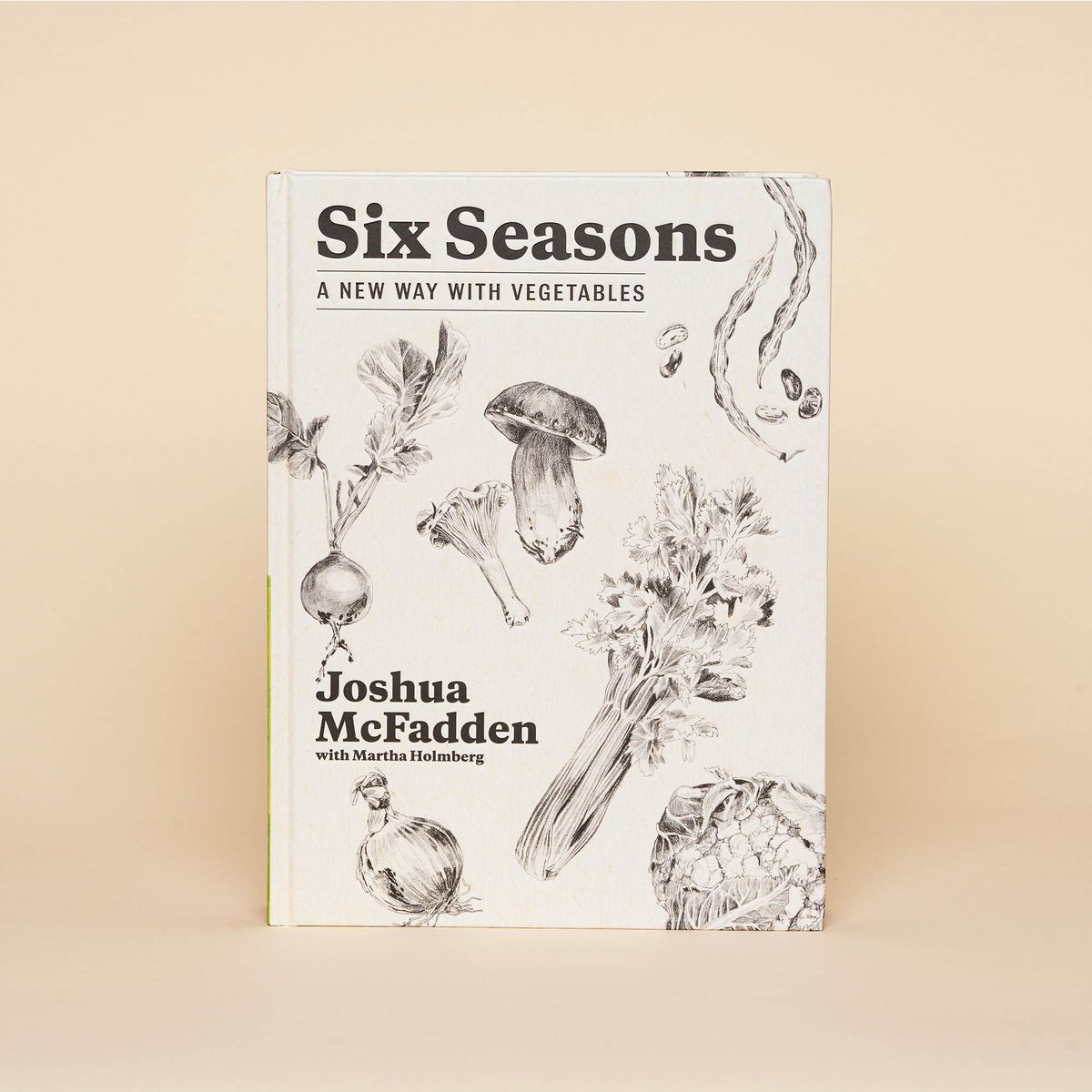 An off-white cookbook with delicate illustrations of beets, onions, mushrooms, green beans and celery