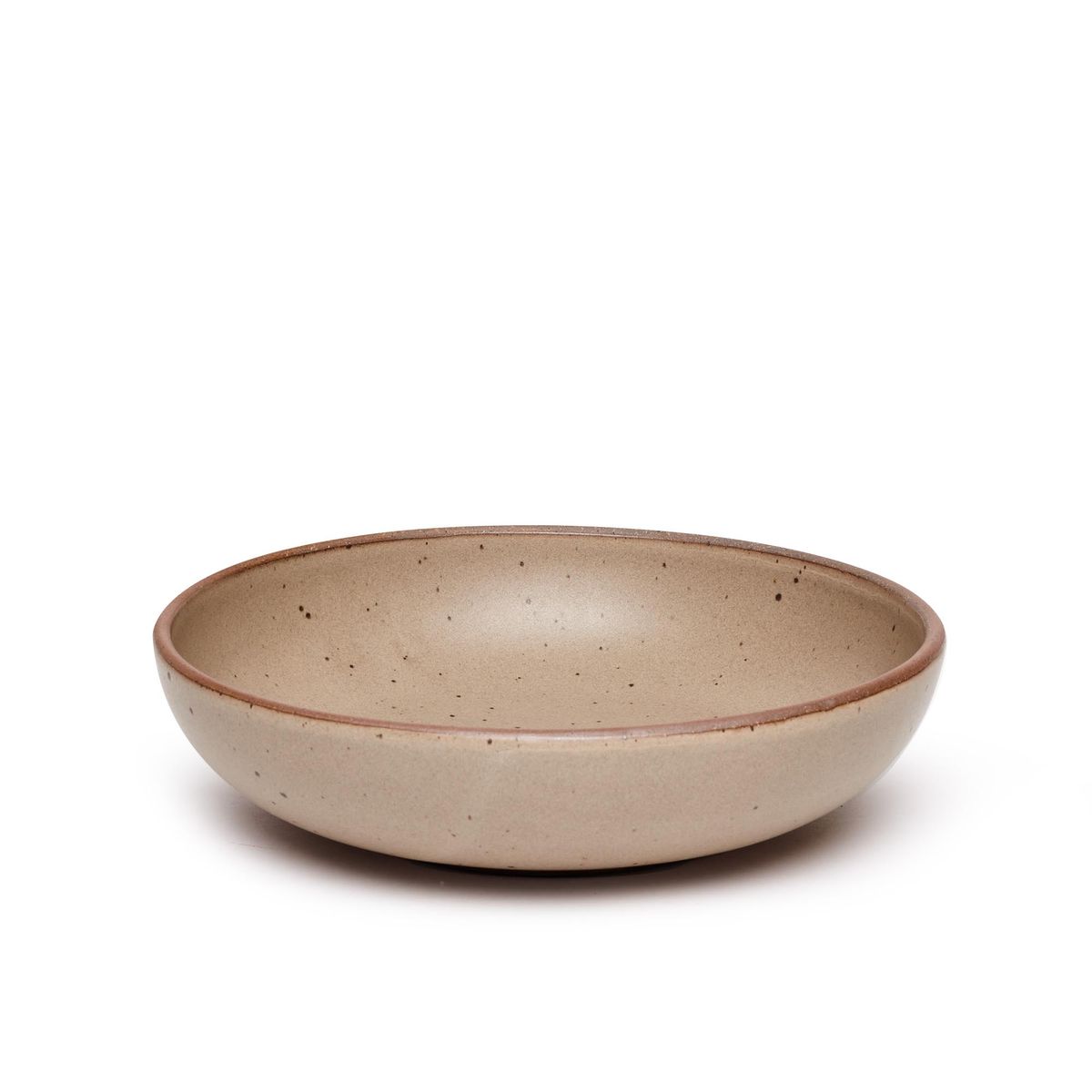 A large shallow serving ceramic bowl in a warm pale brown color featuring iron speckles and an unglazed rim