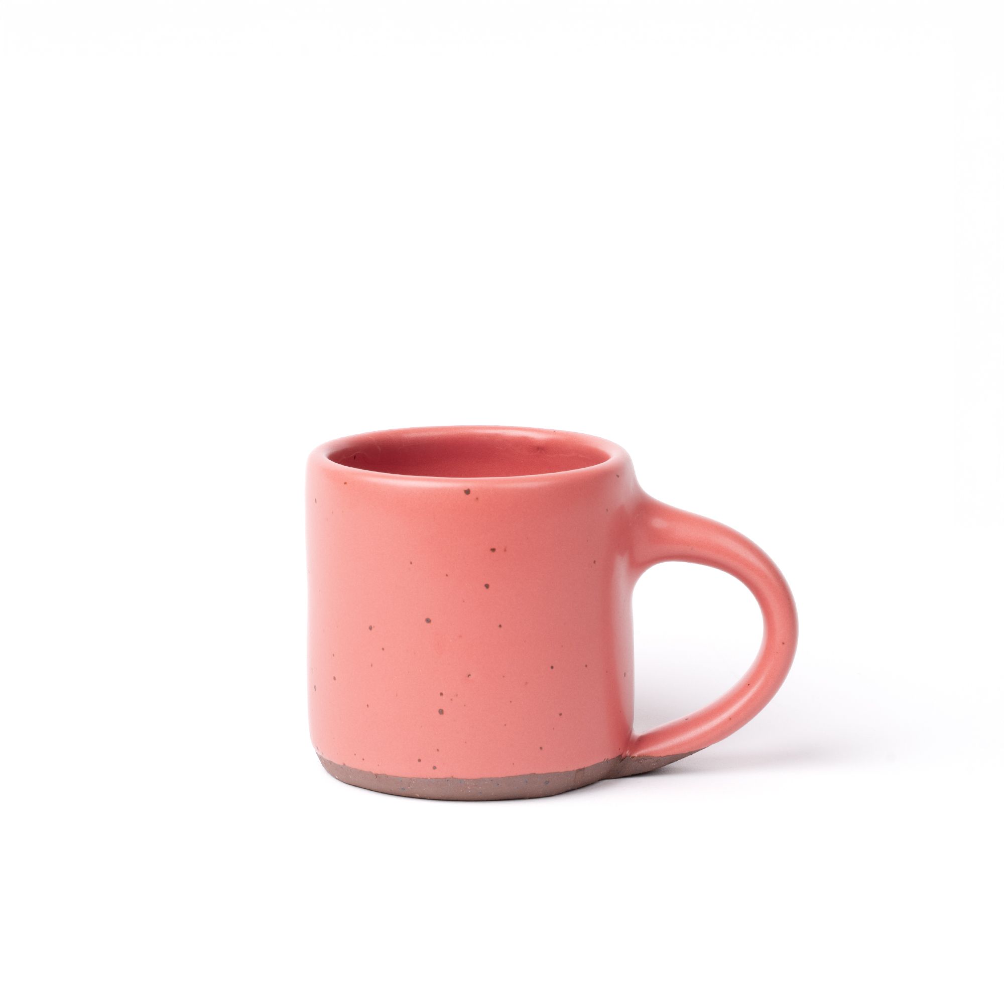 A medium sized ceramic mug with handle in a watermelon pink color featuring iron speckles