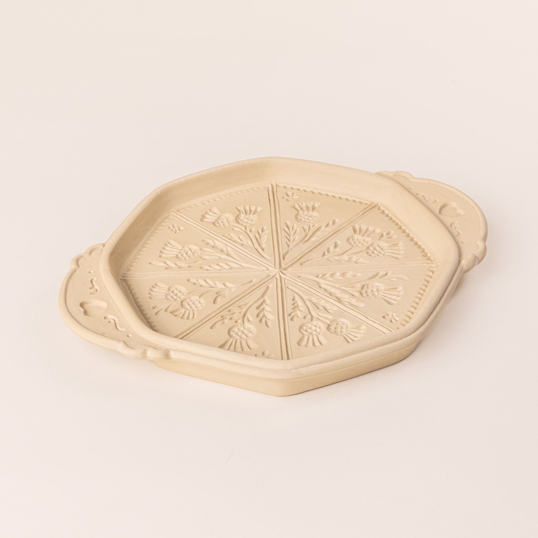 A shortbread pan with a thistle flower design on the bottom