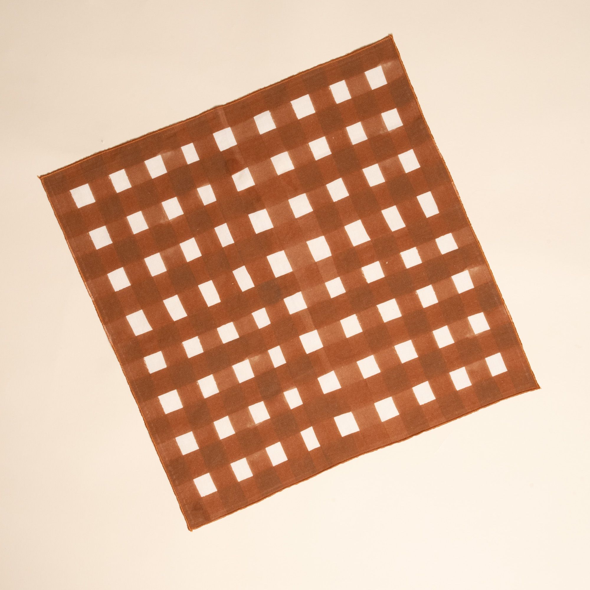 A square linen napkin with a brown and white crosshatch pattern