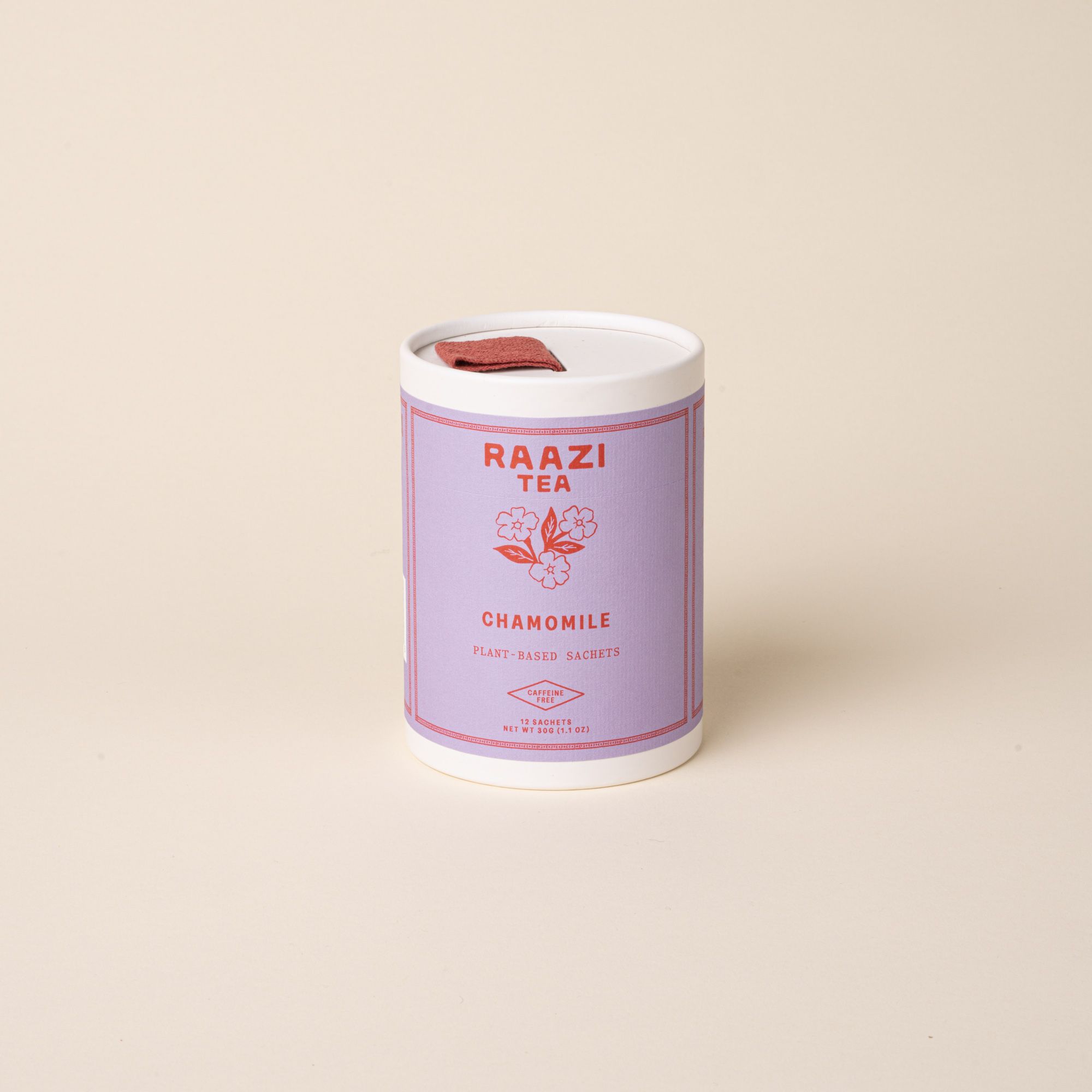 A white cylindrical tin of RAAZI Tea labeled ‘Chamomile’ with a lavender label and red text, topped with a small red pull tab, photographed on a pale beige background.