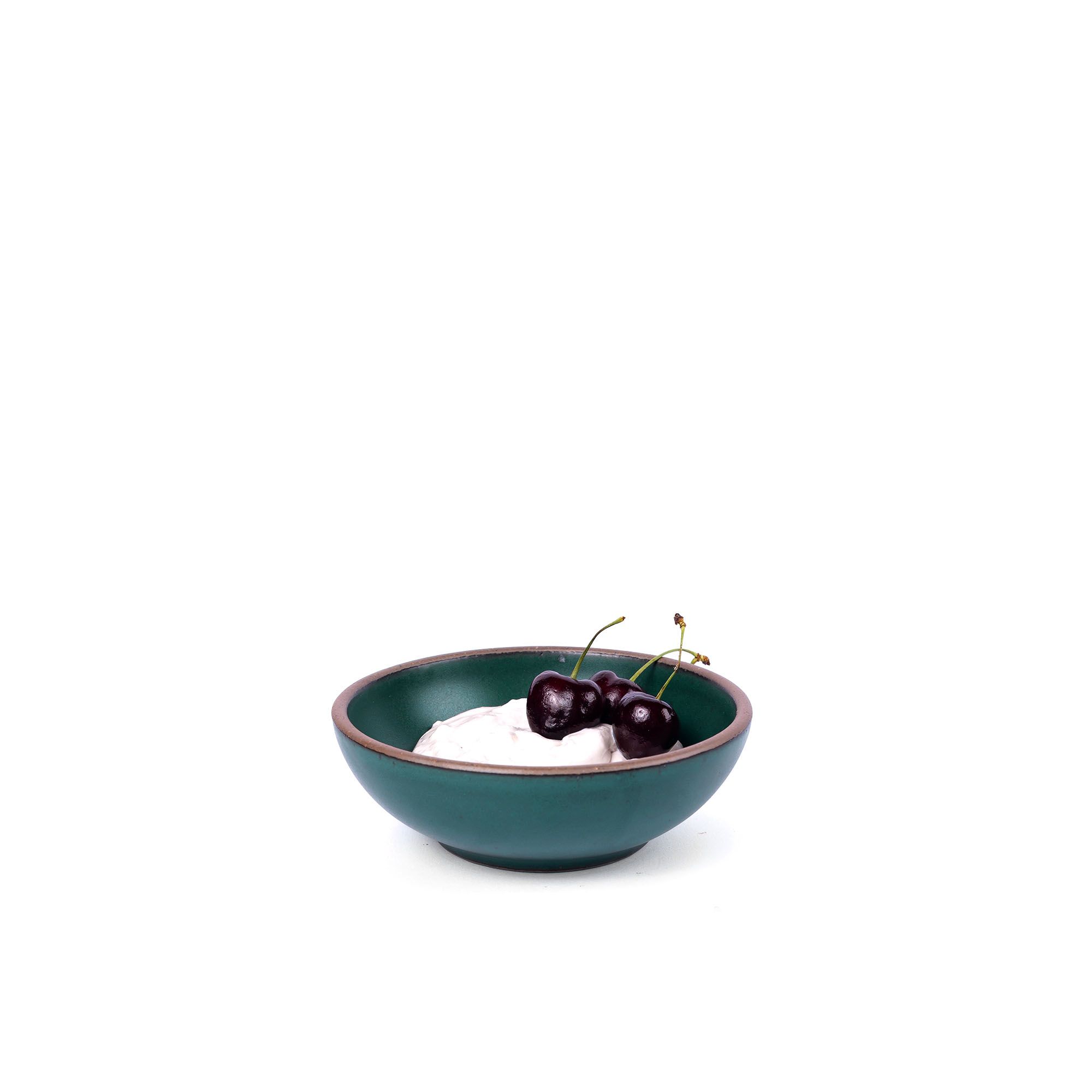 Yogurt and cherries in a small shallow ceramic bowl in a deep dark teal color featuring iron speckles and an unglazed rim