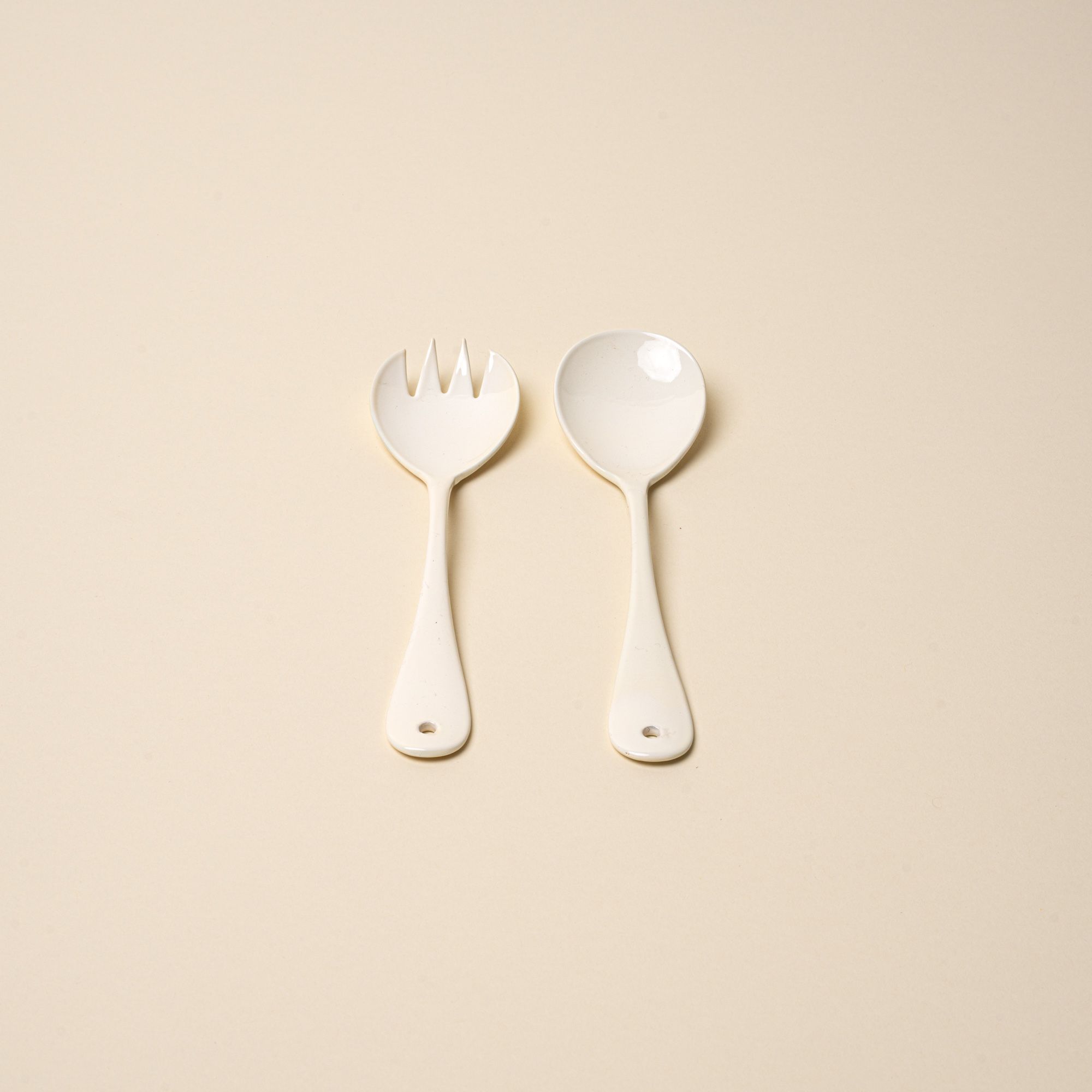 A serving fork and spoon set made of white enamel.