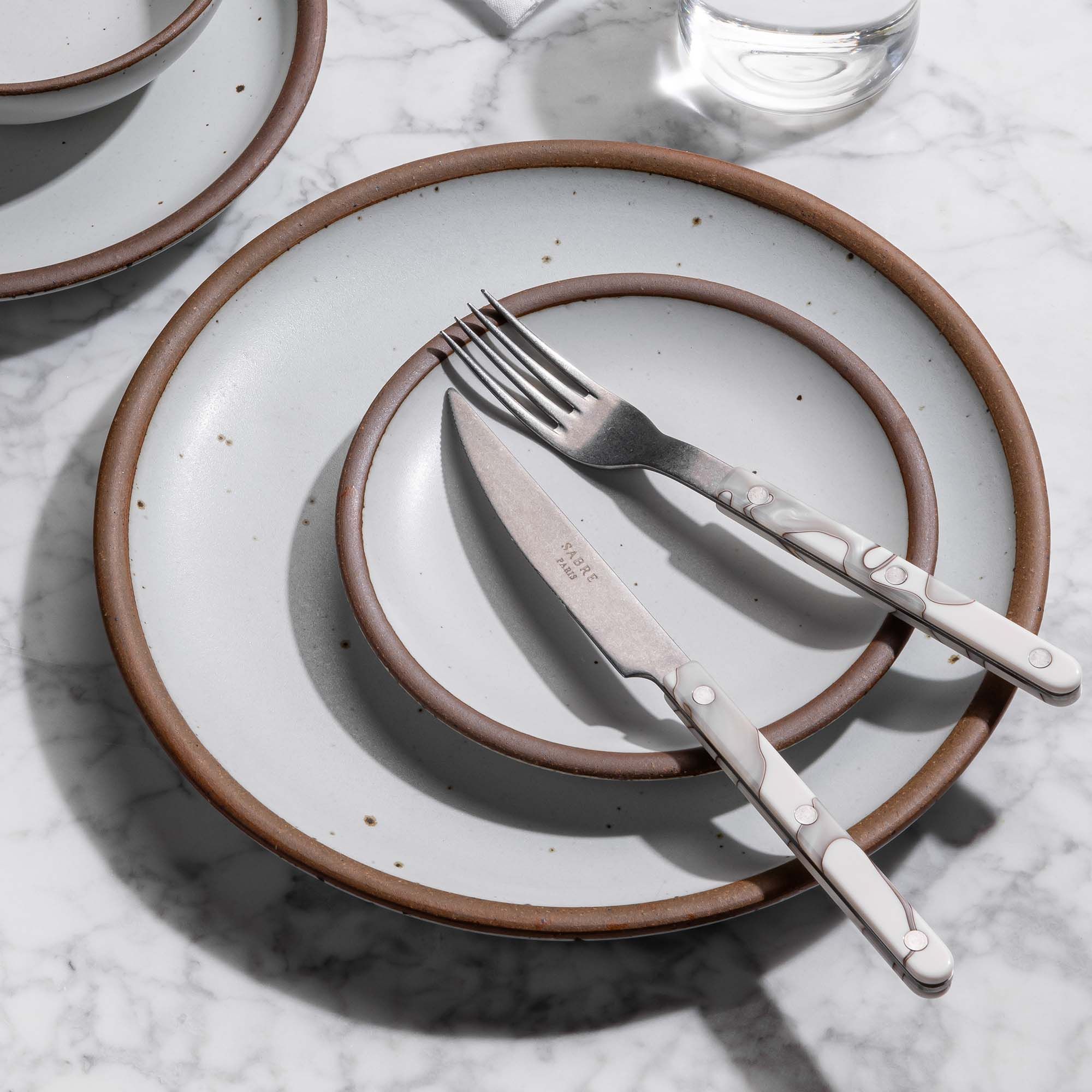 Ceramic dinner plate and cake plate stacked with marbled-handled fork and knife.