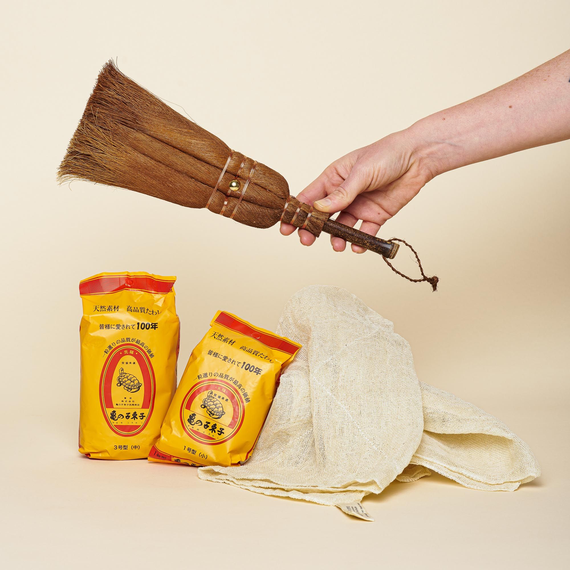 A natural broom for sweeping, two natural brushes for scrubbing, and white towel
