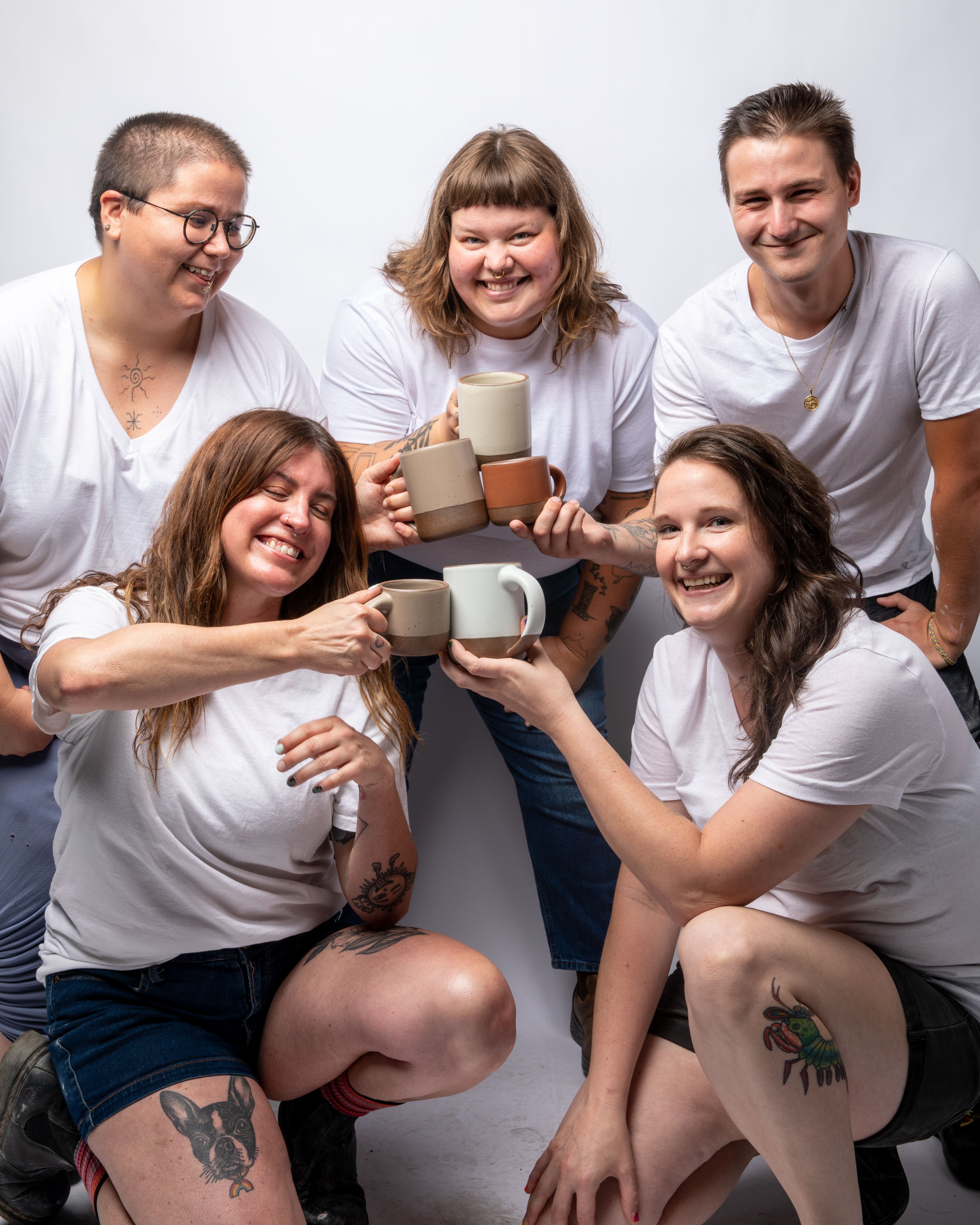 East Fork employees merrily gather on in a photography studio to show off new mugs: The Big Mug and The Small Mug.