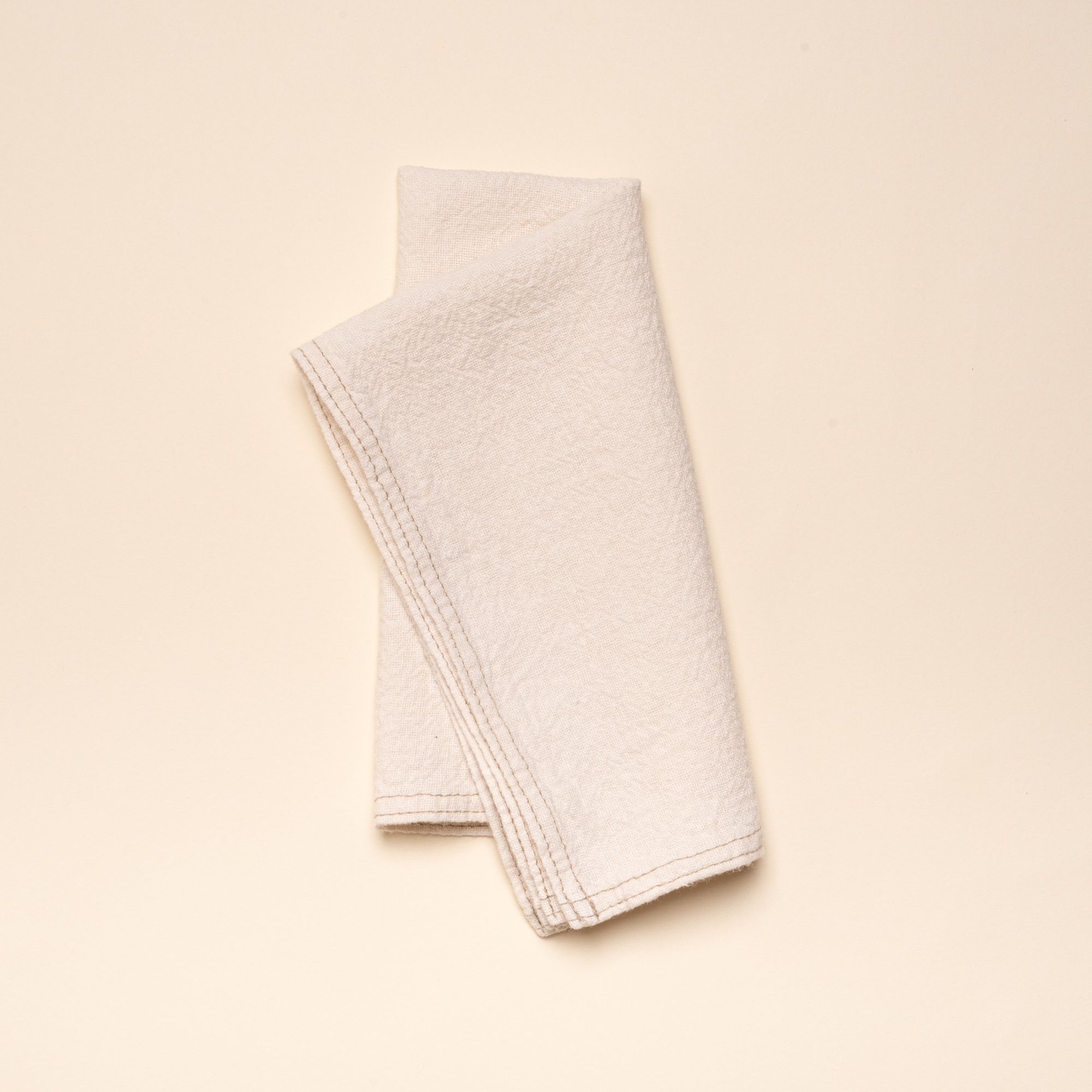 Folded cream linen napkin with sewn edge