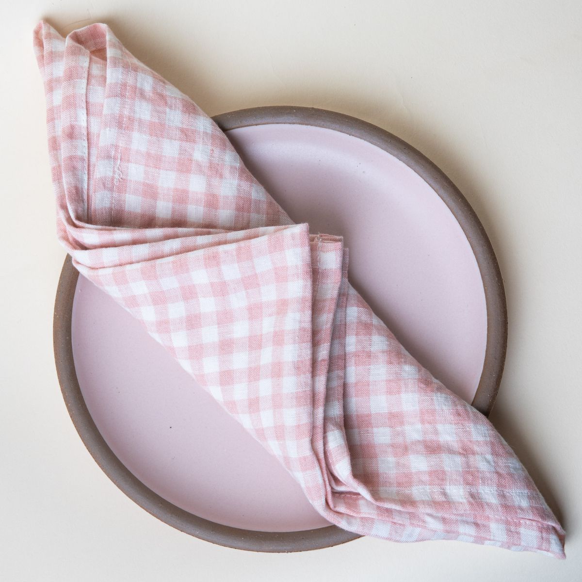 Folded soft pink gingham linen napkin on a soft pink plate