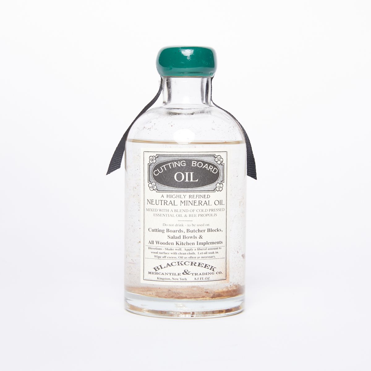 Clear bottle full of liquid with an old-timey label that reads "Cutting Board Oil" with green wax covering the top