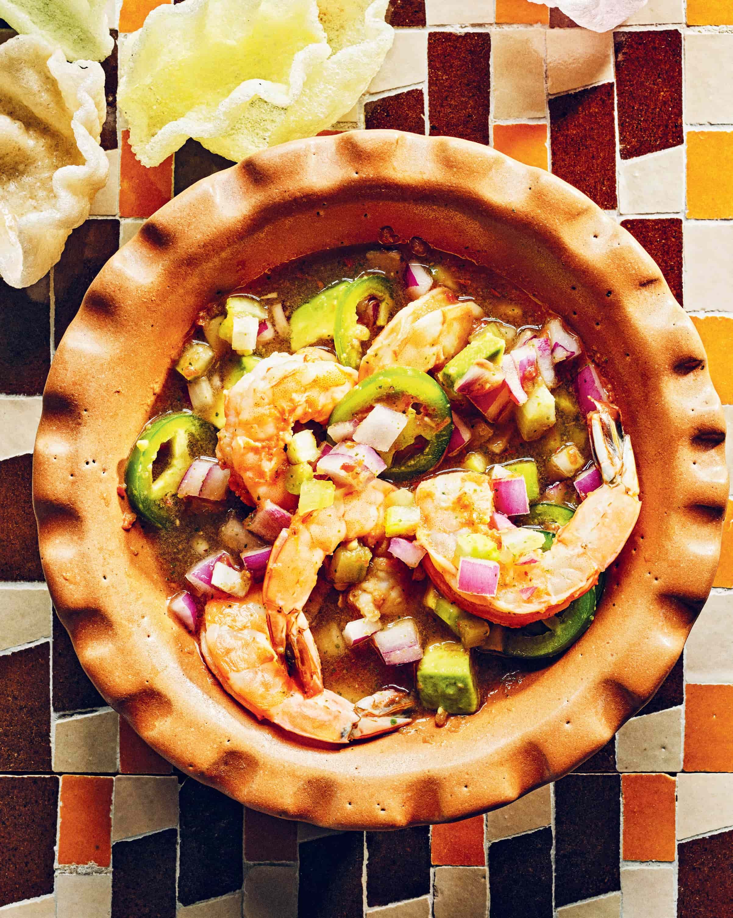 A colorful image featuring a bowl of a shrimp cocktail with prawn crackers