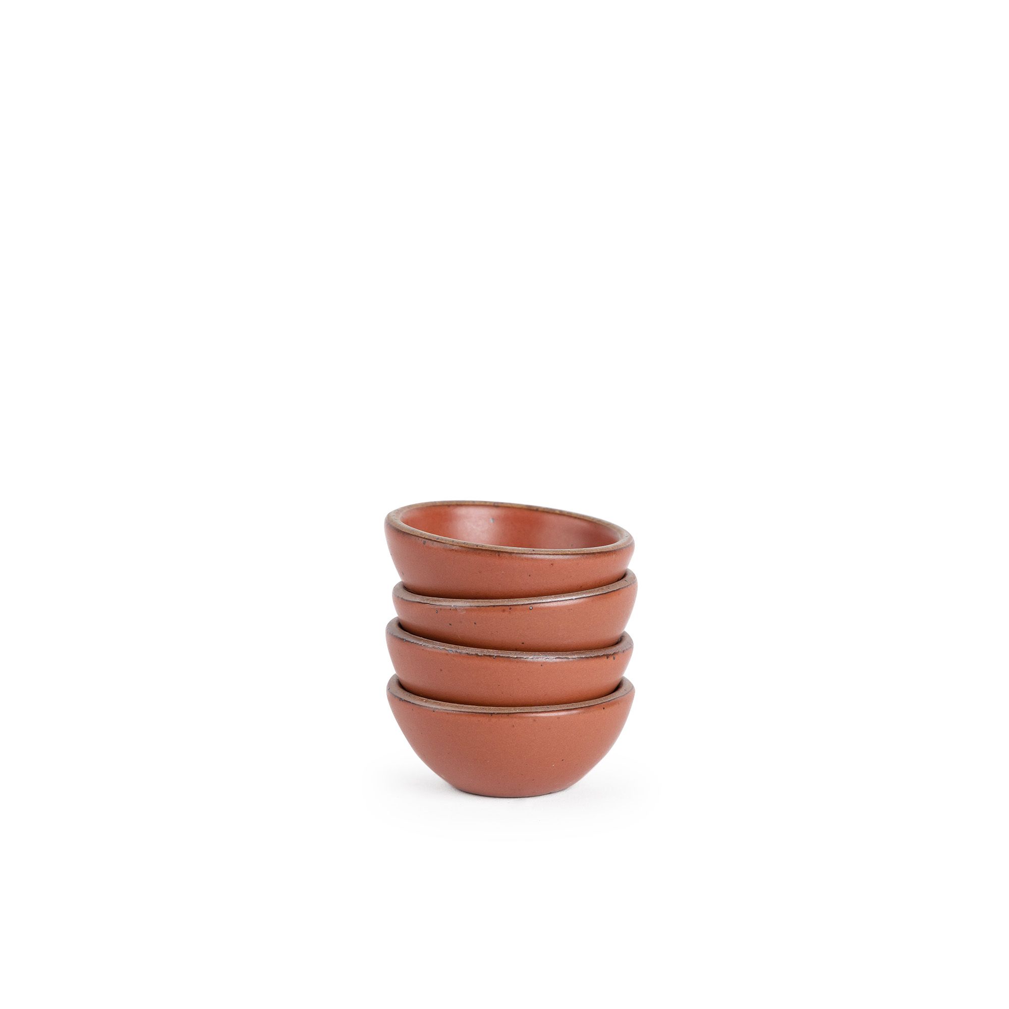 A stack of 4 tiny rounded ceramic bowls in a cool burnt terracotta color featuring iron speckles and an unglazed rim