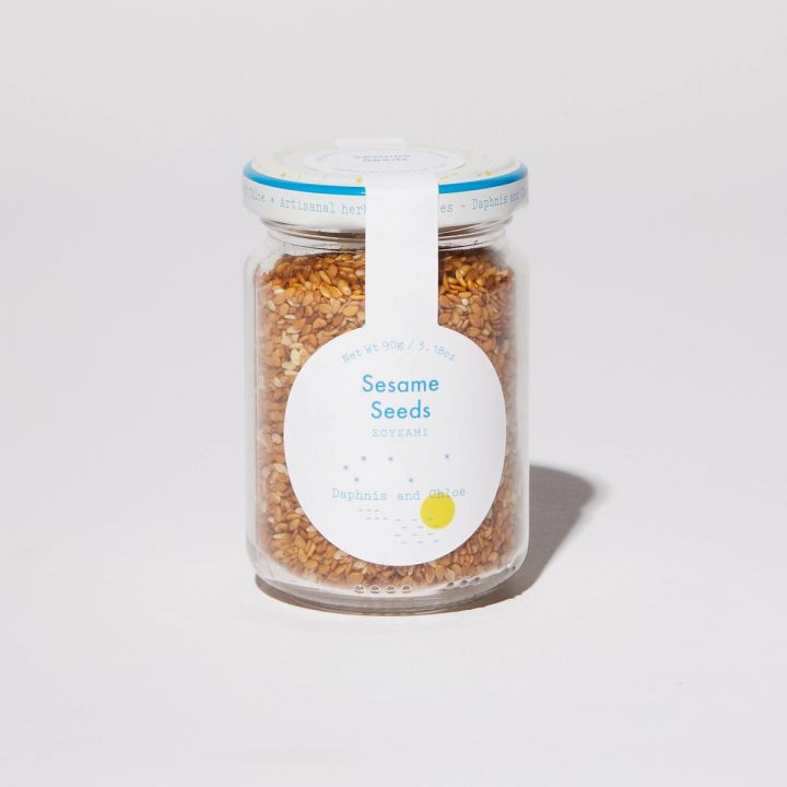 Clear glass jar filled with sesame seeds featuring a round white label that reads "Sesame Seeds" "Daphnis and Chloe"
