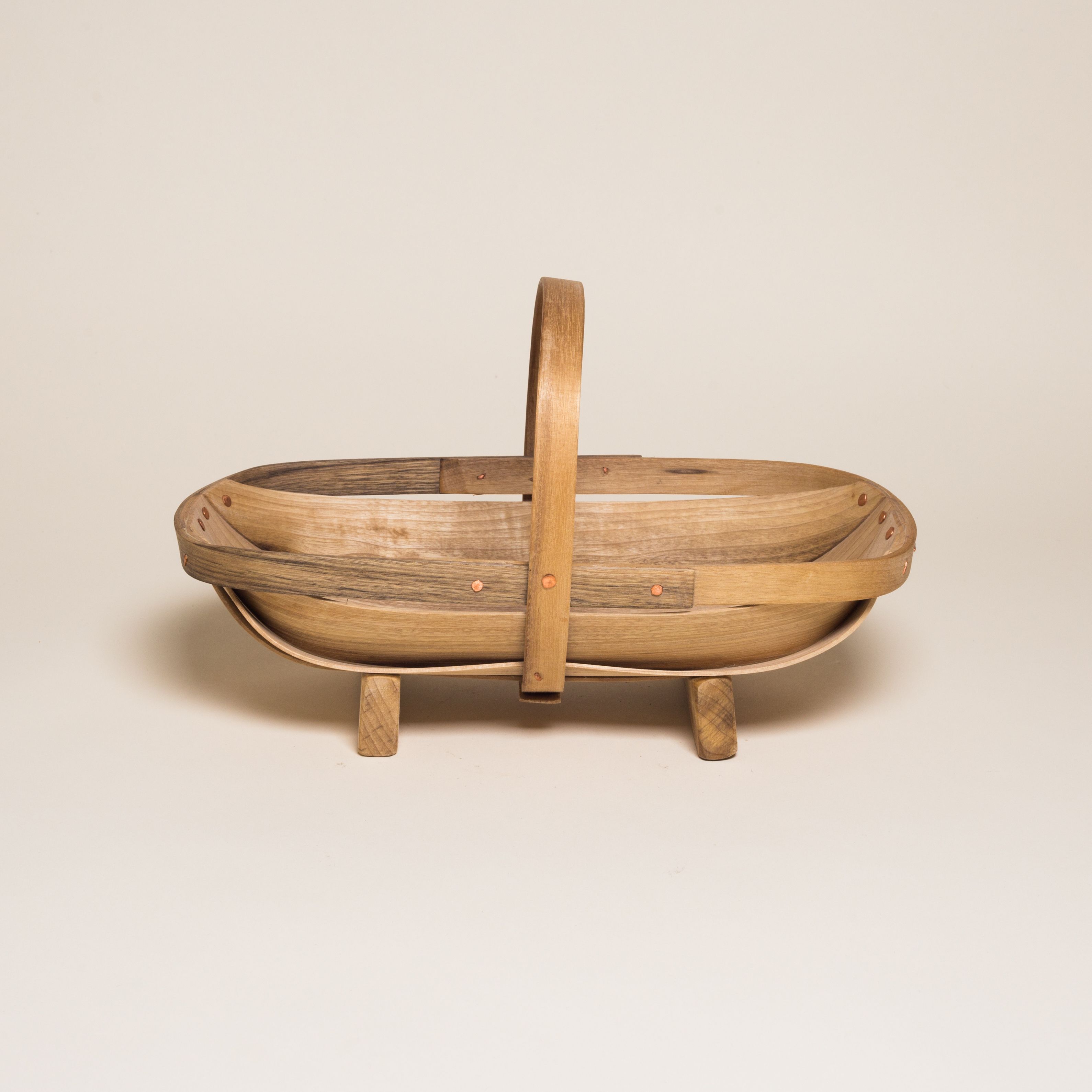 A wooden trug basket with two feet and a handle that encircles the center