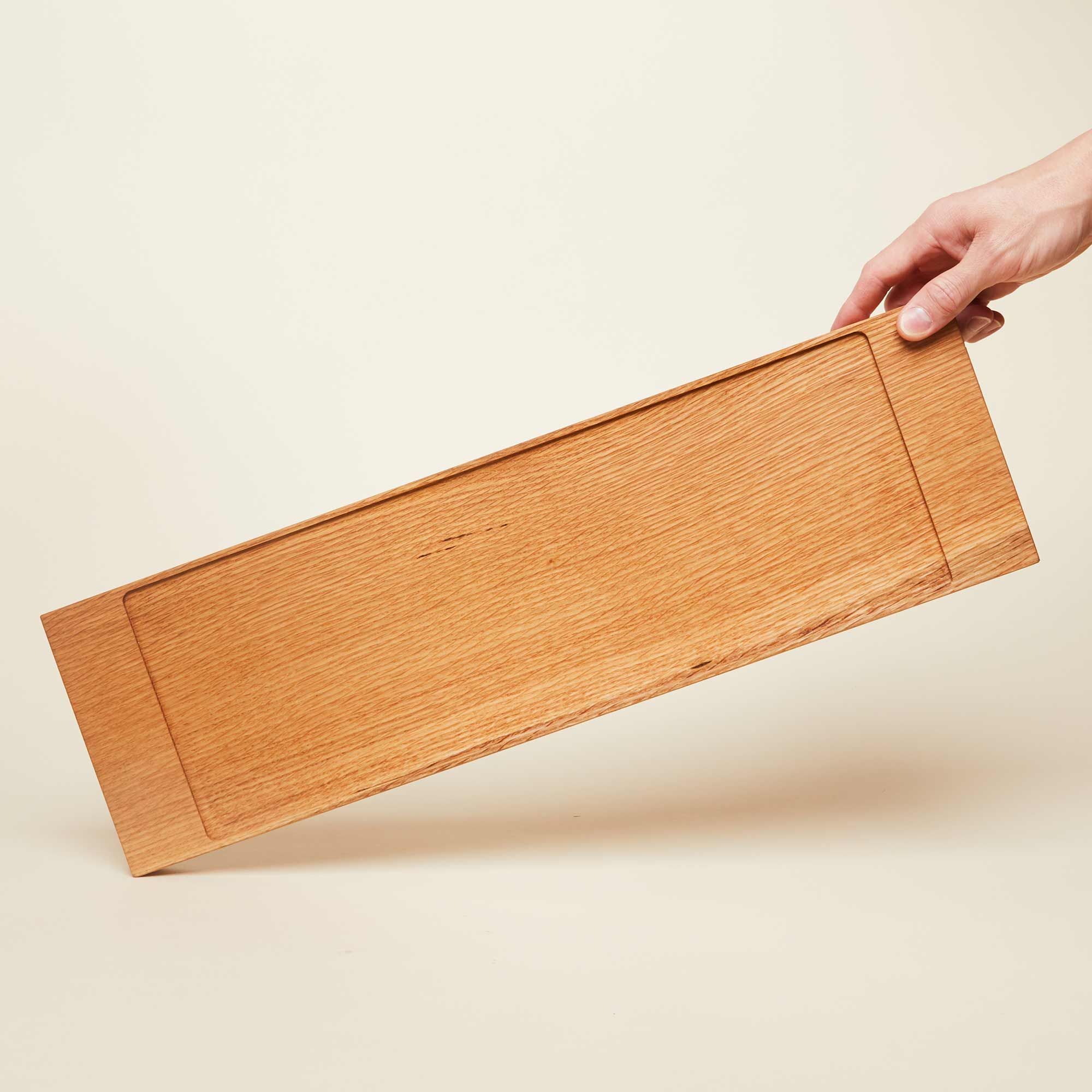 A narrow rectangle of light brown wood with a vertical groove at either end