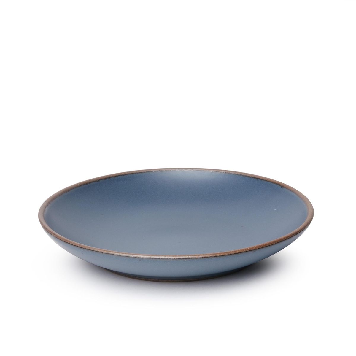 A large ceramic plate with a curved bowl edge in a toned-down navy color featuring iron speckles and an unglazed rim.