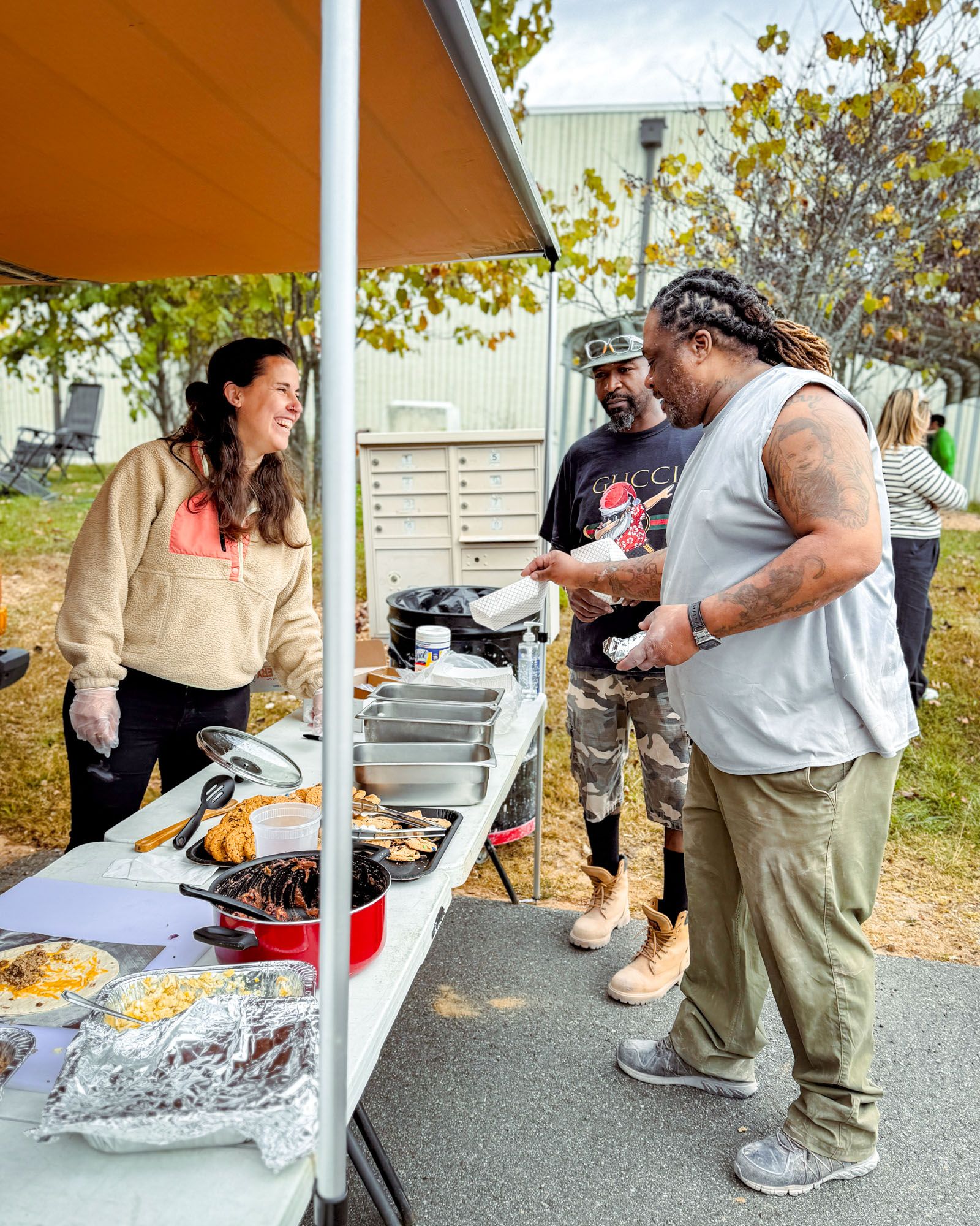 Outside, East Fork employees are smiling and gather to grab food from a table