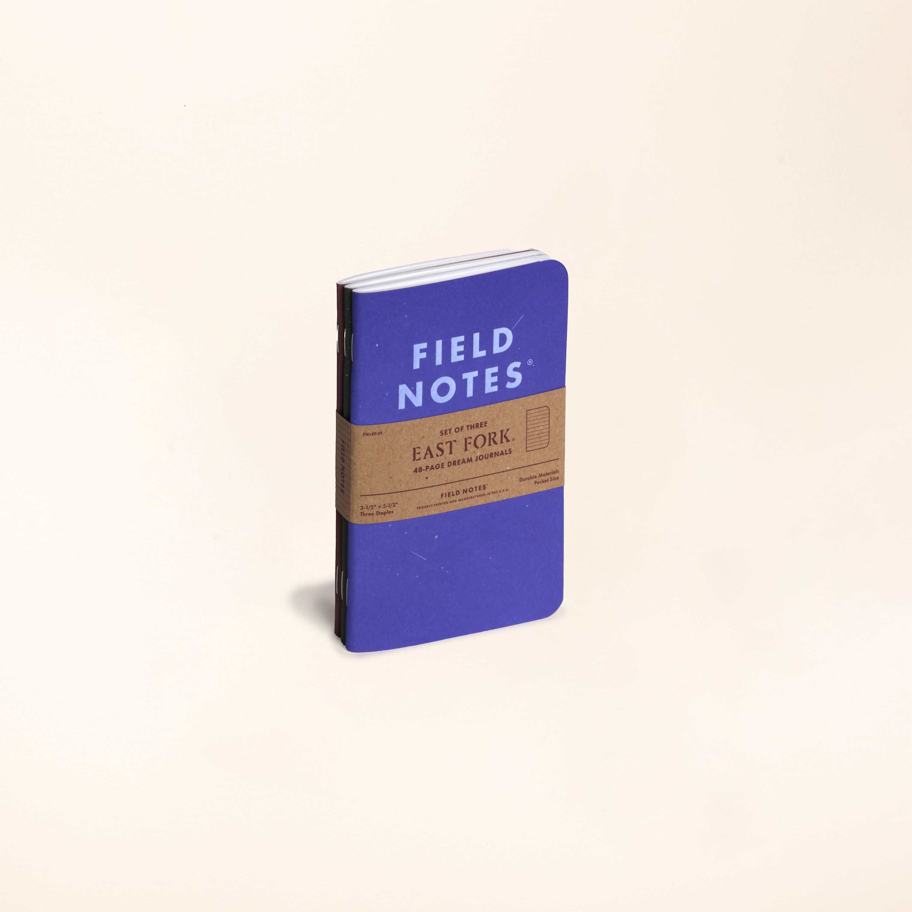 A 3 pack of Field Notes Journal standing up with a kraft paper belly band around it.