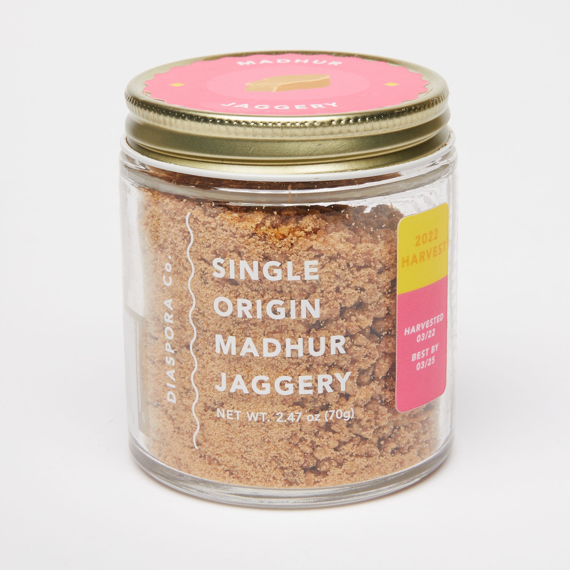 Short glass jar with a metal screw top with a pink label, the jar reads "Single Origin Madhur Jaggery"
