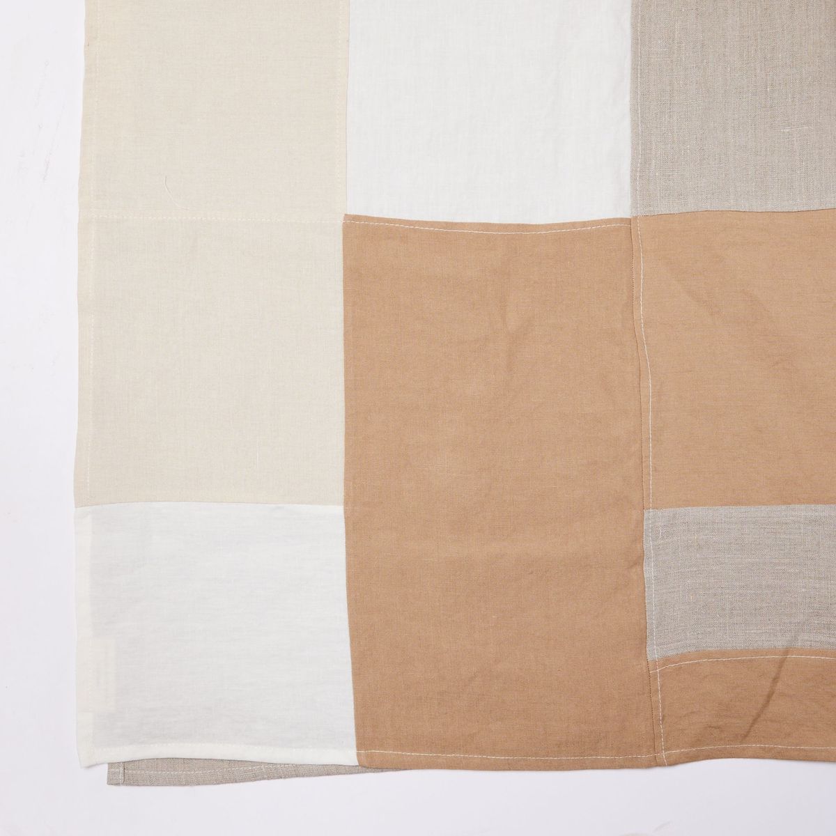 Corner of tablecloth with tan, white, beige, rectangular shapes