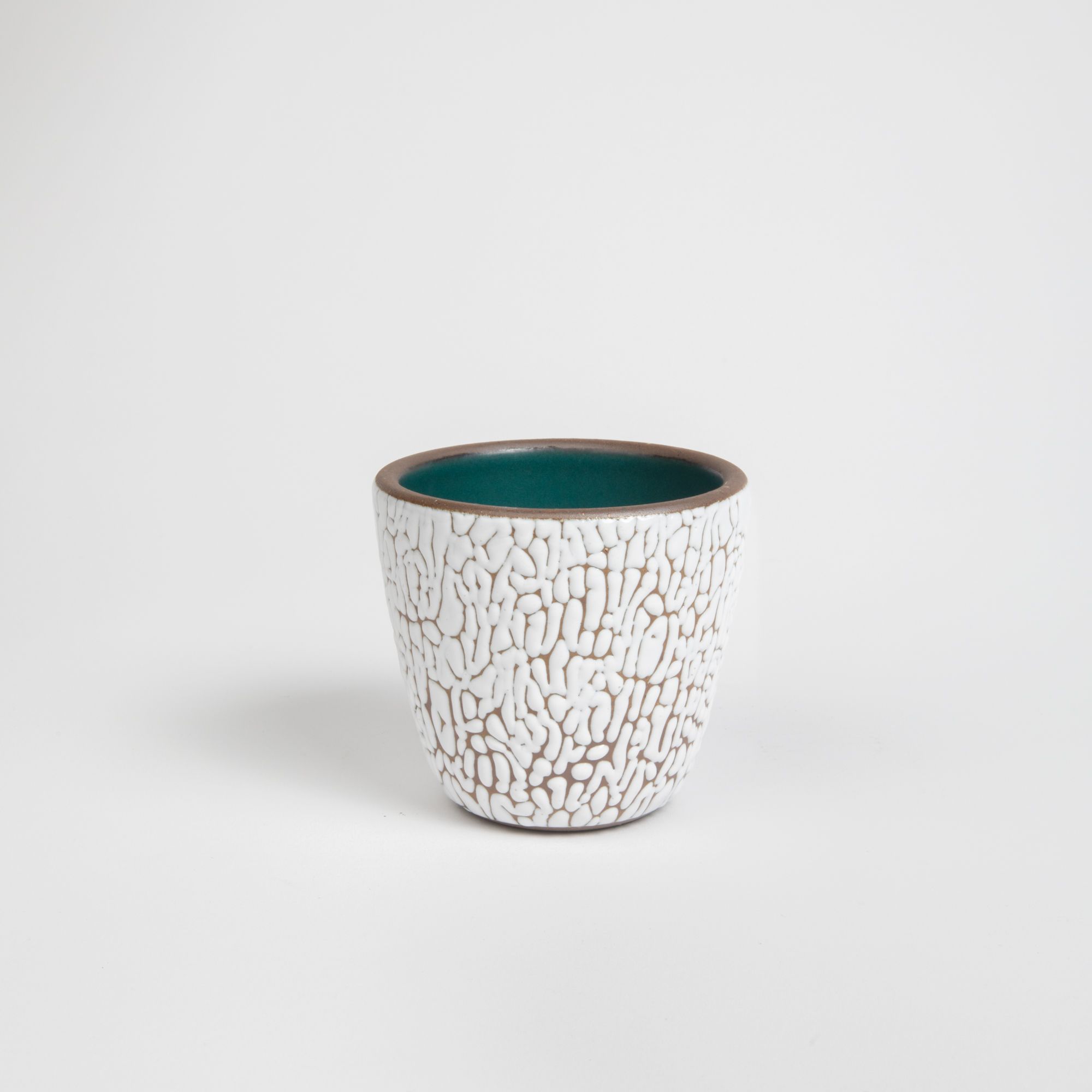 A small ceramic cup with cracked texture and the interior being dark teal.