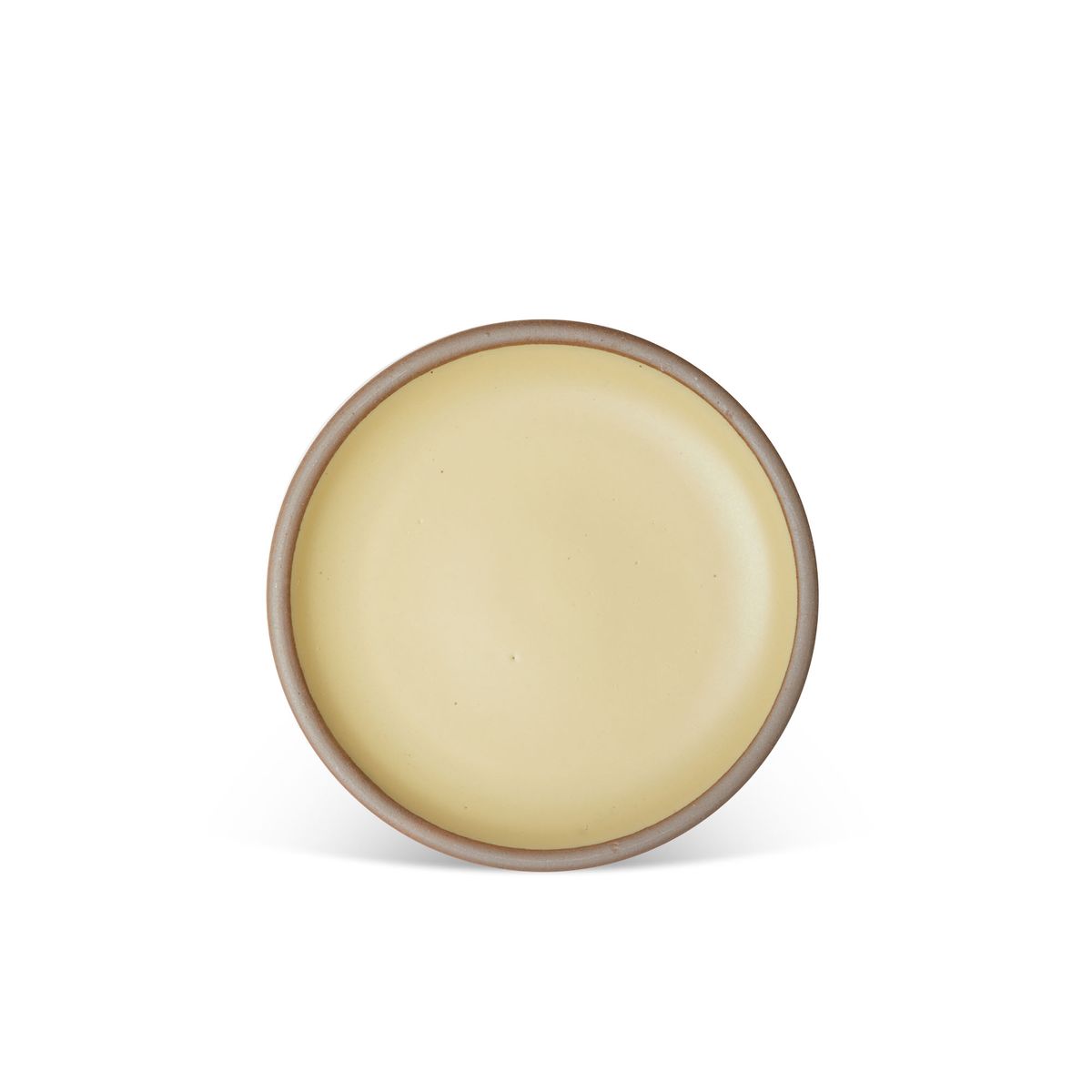A medium sized ceramic plate in a light butter yellow color featuring iron speckles and an unglazed rim.