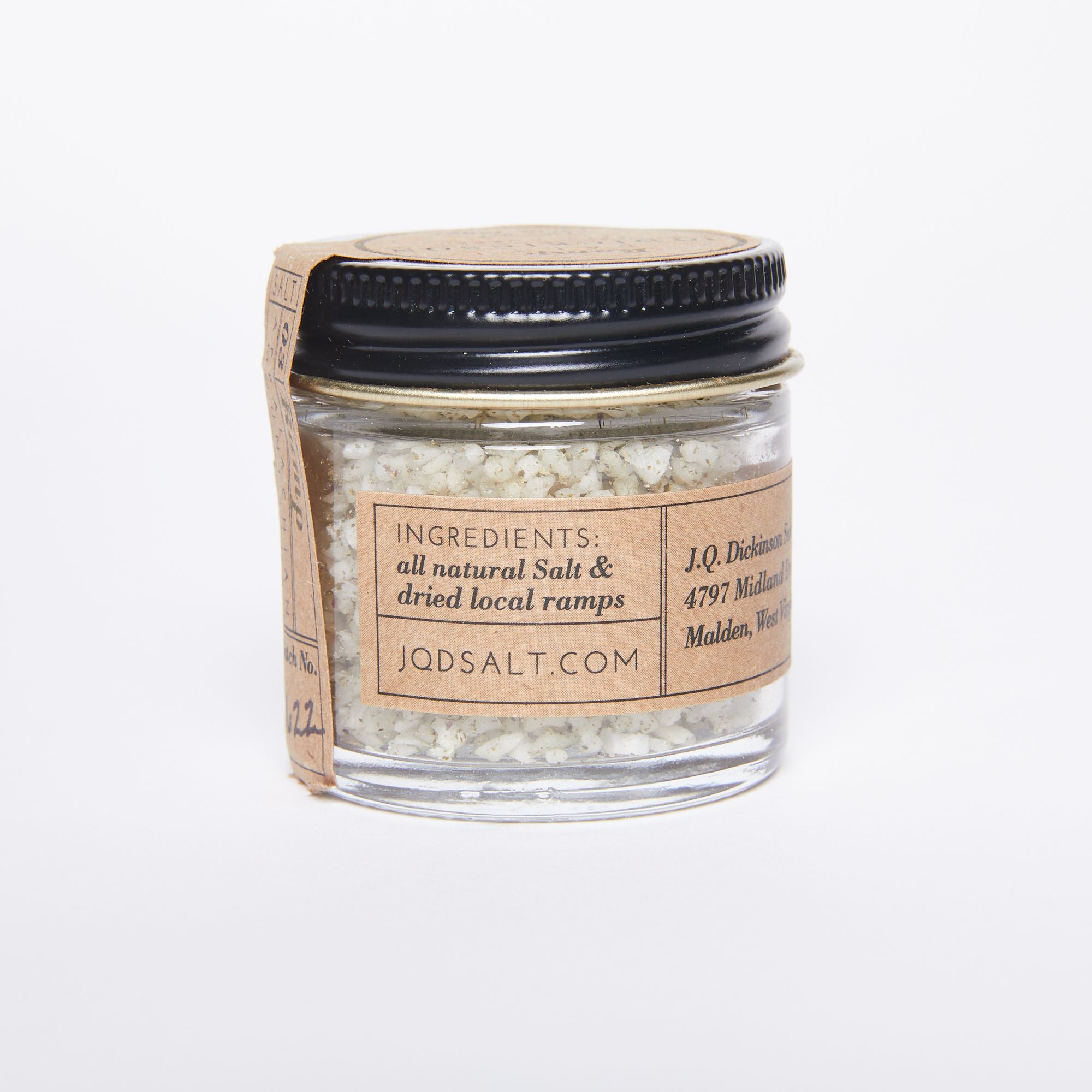 Round glass jar full of large salt crystals with a black screw lid and a natural color label with a list of ingredients: all natural salt, dried local ramps