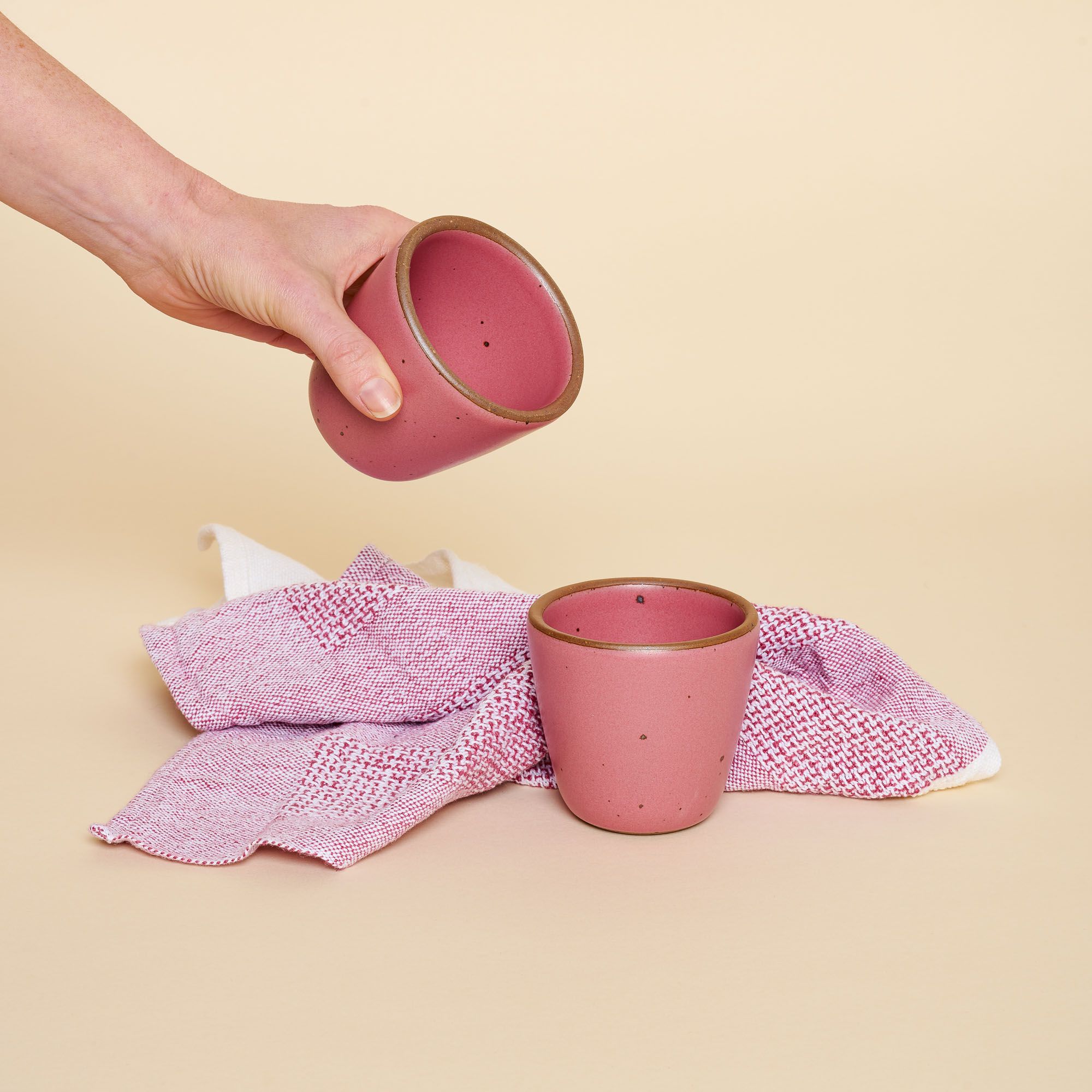A pair of chai kulhads – handleless cups – in Rococo, a hot pink, photographed with a soft, organic cotton and linen blend tea towel in a matching hue.